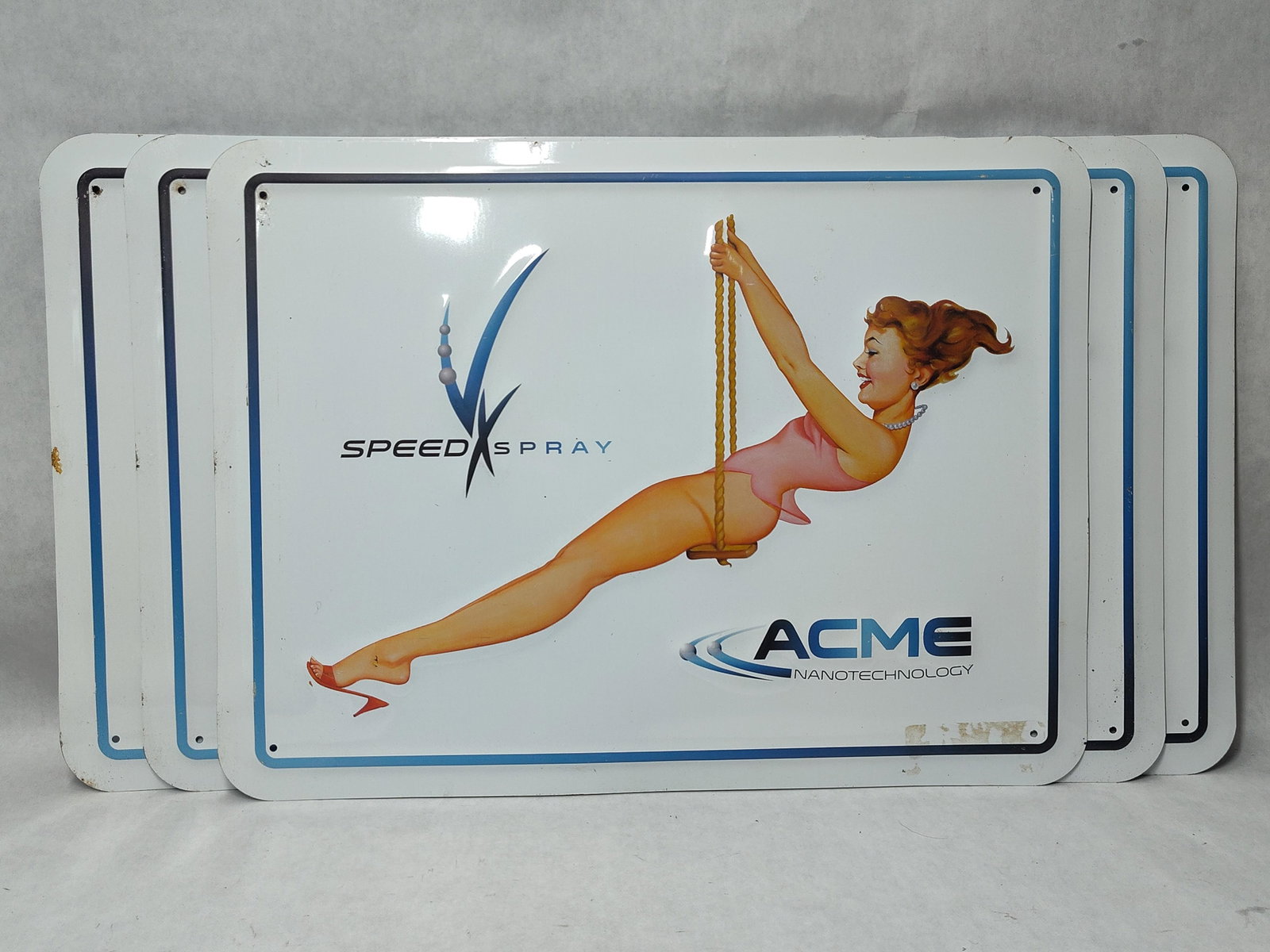Set 4 Acme Nanotechnology Pin-Up Metal Signs: A set of four stamped and embossed metal advertising signs featuring a contemporary retro-style design. The central imagery depicts a woman with auburn hair in a mid-20th-century aesthetic pin-up