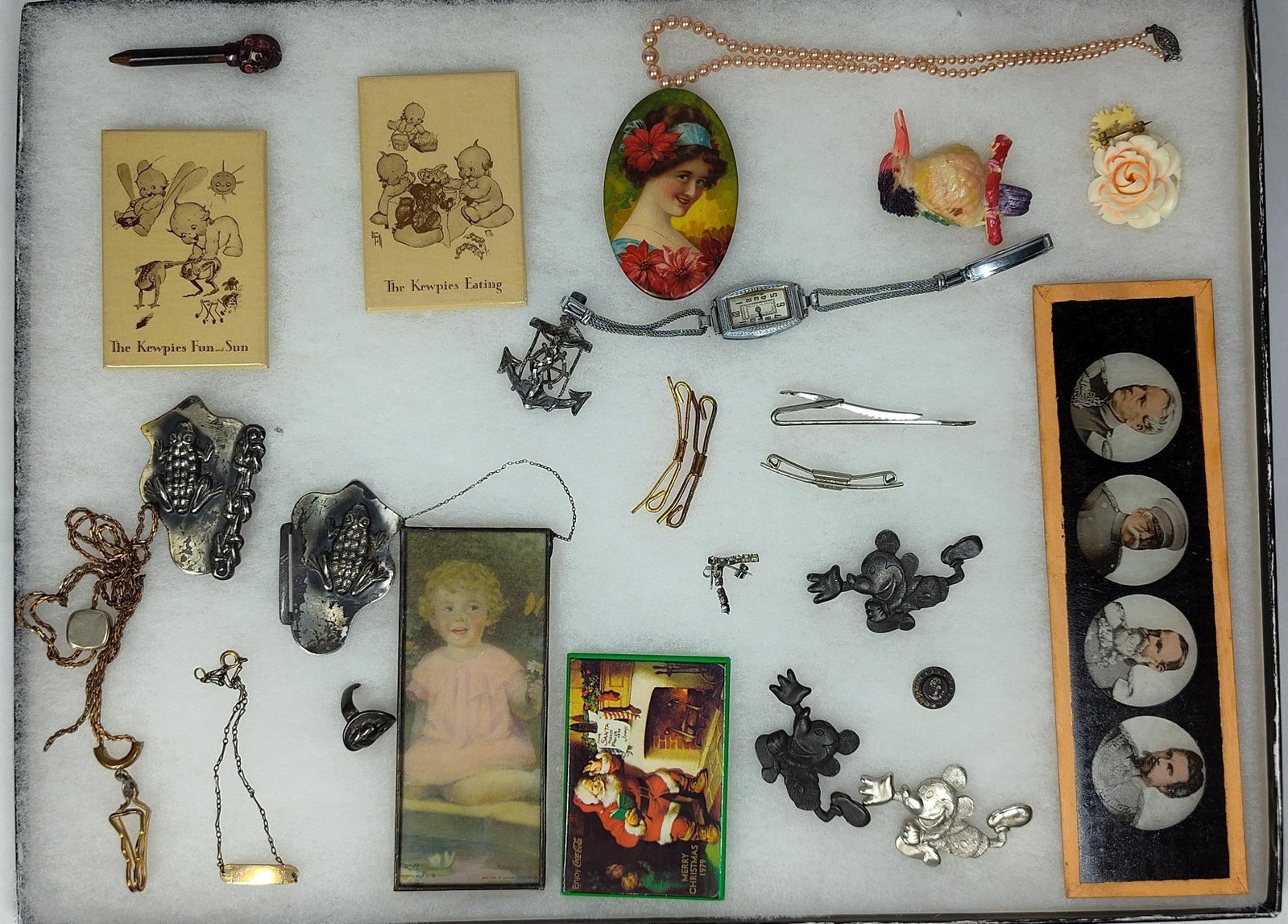 A collection of Early Jewelry, Smalls, and Ephemera: This lot comprises an eclectic collection of and antique jewelry, accessories, and printed ephemera. Notable items include two printed cardstock illustrations titled The Kewpies Fun and Sun and The