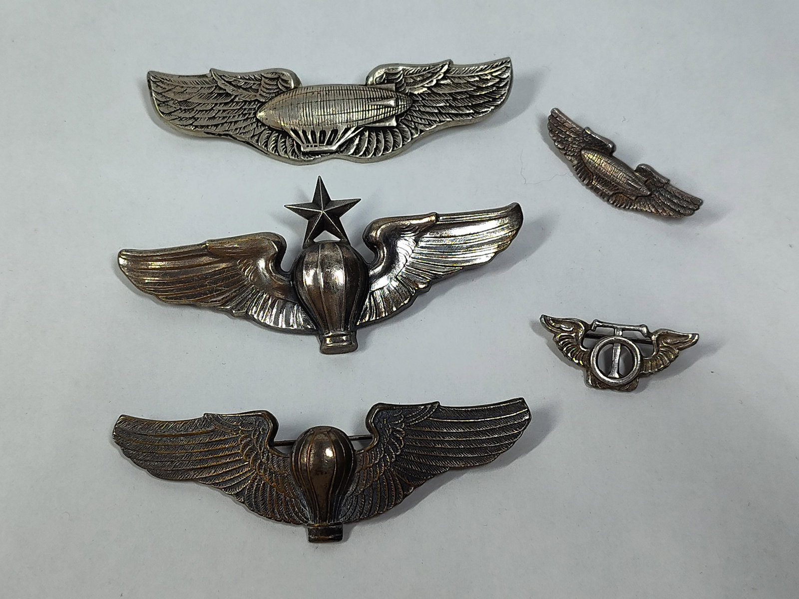 WWII USAAF Str. Aviation & Parachutist Badges: A collection of World War II era United States military qualification and rating badges. The group consists of five distinct items including three full-size wings and two miniature lapel badges. The