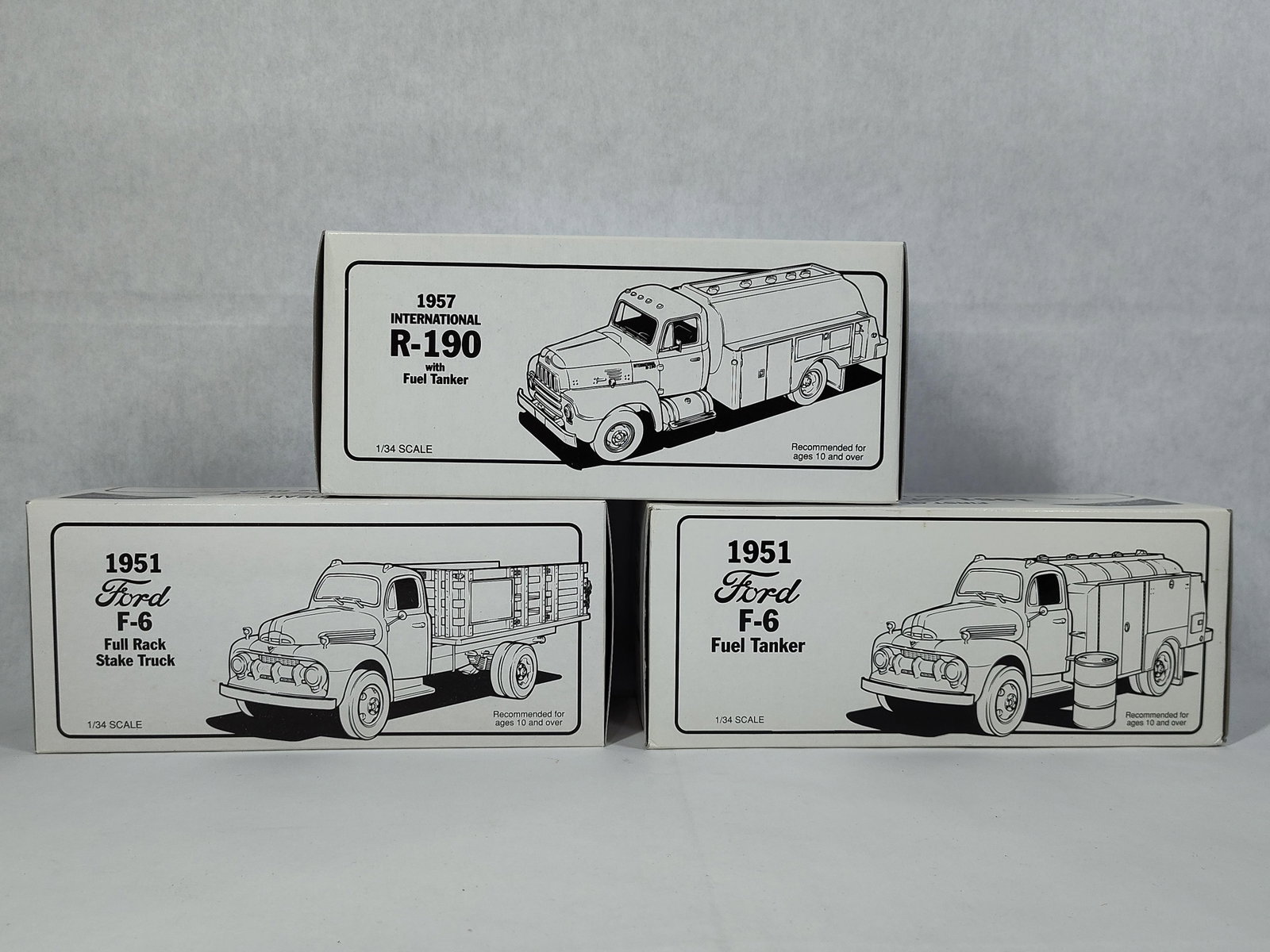 Three First Gear 1/34 Scale Model Trucks: This lot features three 1/34 scale model trucks manufactured by First Gear as part of their precision collectible series. The group includes a 1957 International R-190 with a fuel tanker finished in