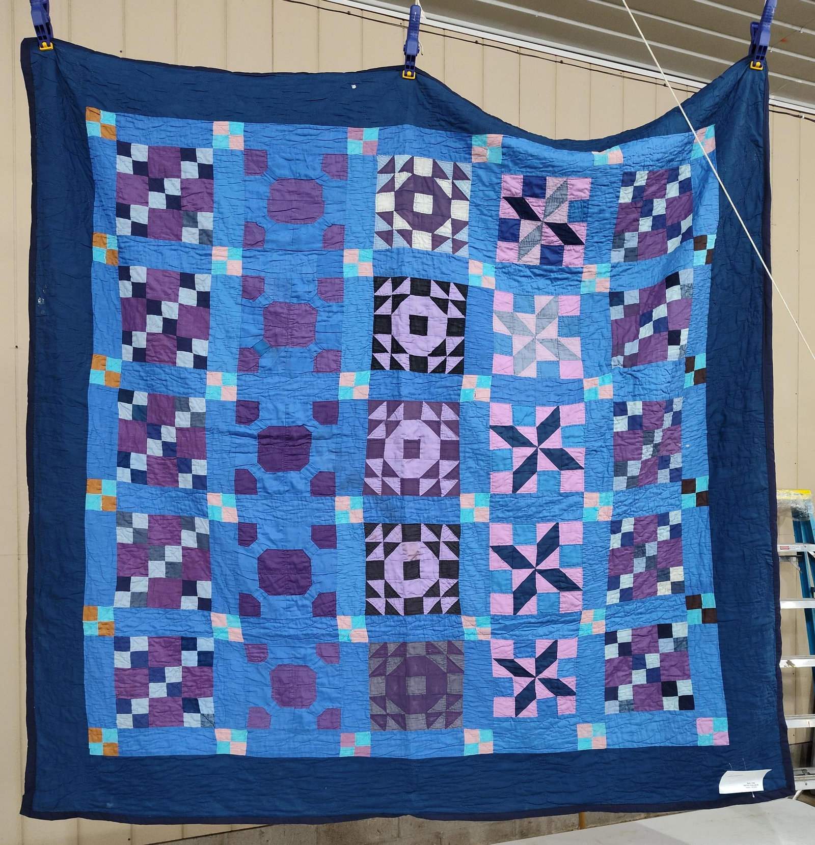 Blue & Purple Geometric Hand-Quilted Sampler Quilt: 74 x 76. This is a hand-quilted cotton sampler quilt featuring an array of traditional pieced geometric patterns. The quilt top is organized into five vertical columns of blocks joined with medium