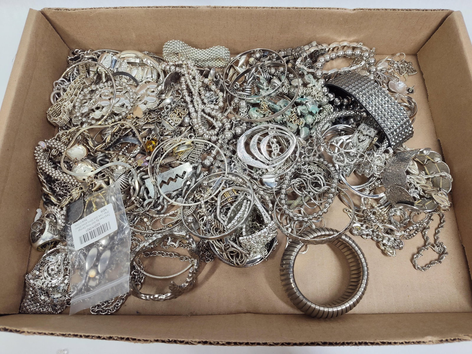 Silver-Tone Costume Jewelry Collection: This is a large bulk lot of assorted silver-tone costume jewelry, primarily featuring necklaces, bracelets, earrings, and rings. The collection incorporates a wide array of styles, including