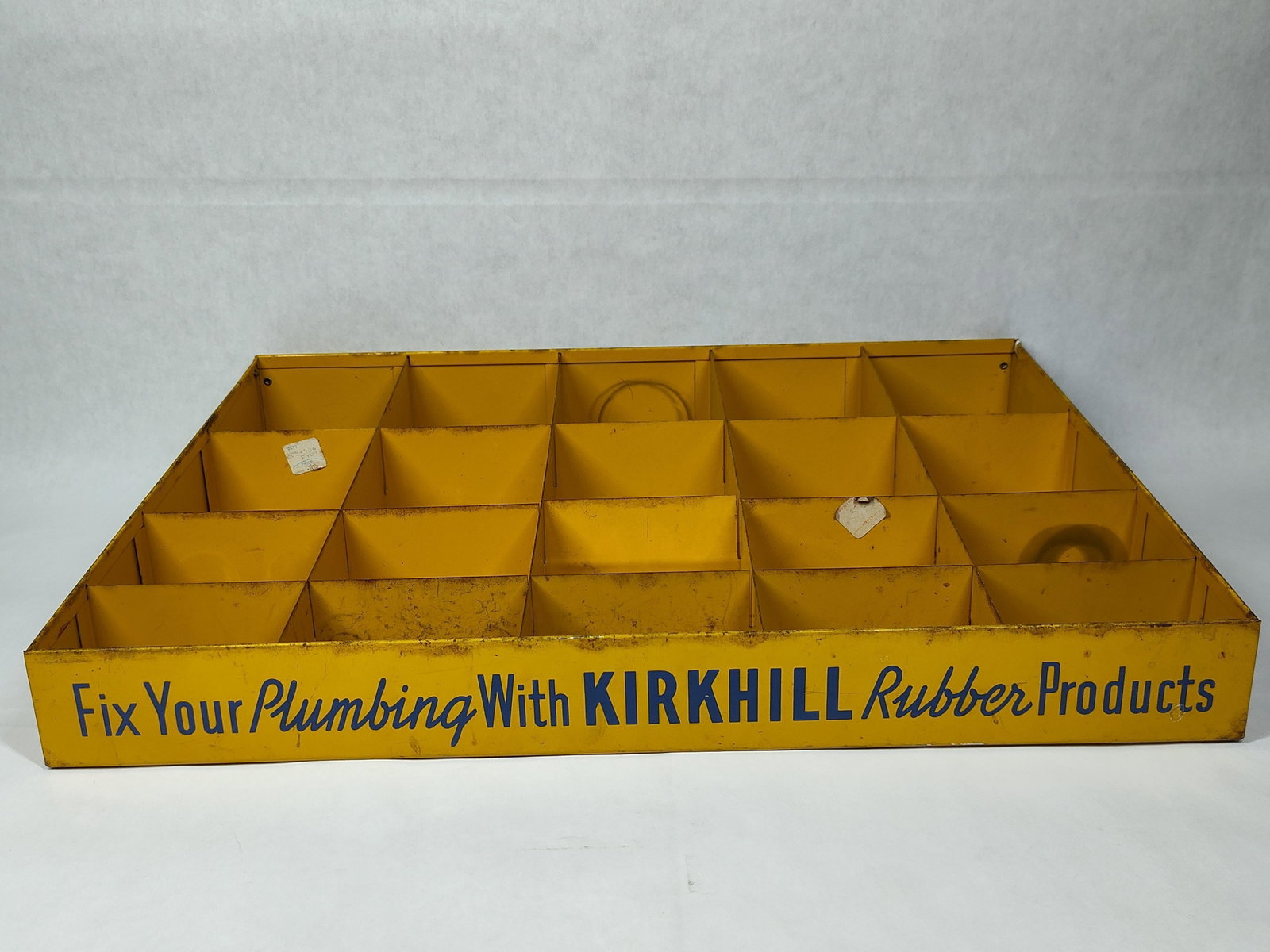 Kirkhill Rubber Products Metal Advertising Bin: A mid-20th century industrial advertising display bin manufactured for Kirkhill Rubber Products. Constructed from yellow-painted sheet metal, the unit features twenty individual compartments arranged