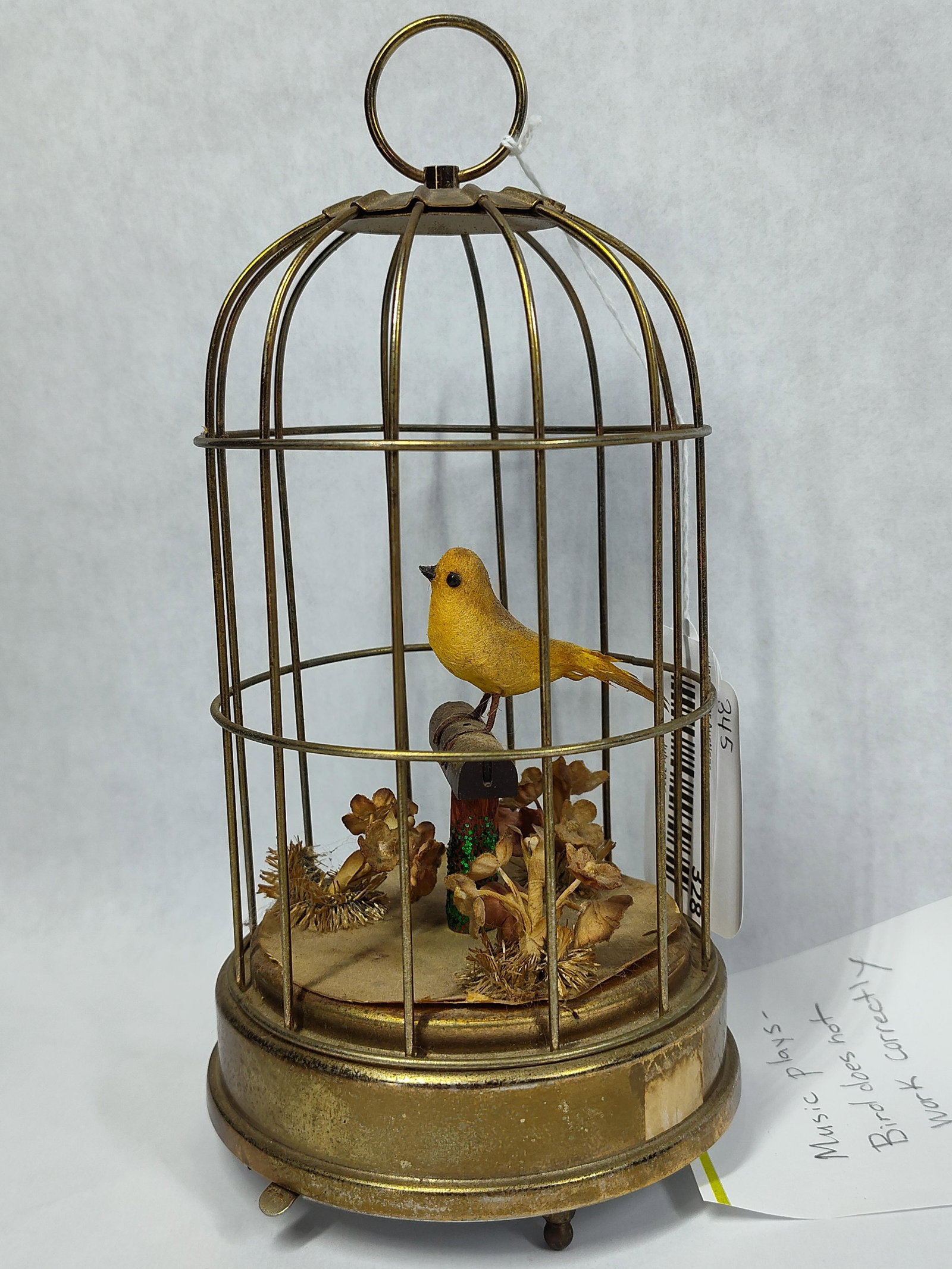 Mechanical Musical Birdcage Automaton: A mechanical birdcage automaton attributed to Schmid Brothers. The item features a single yellow-feathered artificial bird perched upon a decorative stand, surrounded by dried floral elements at the