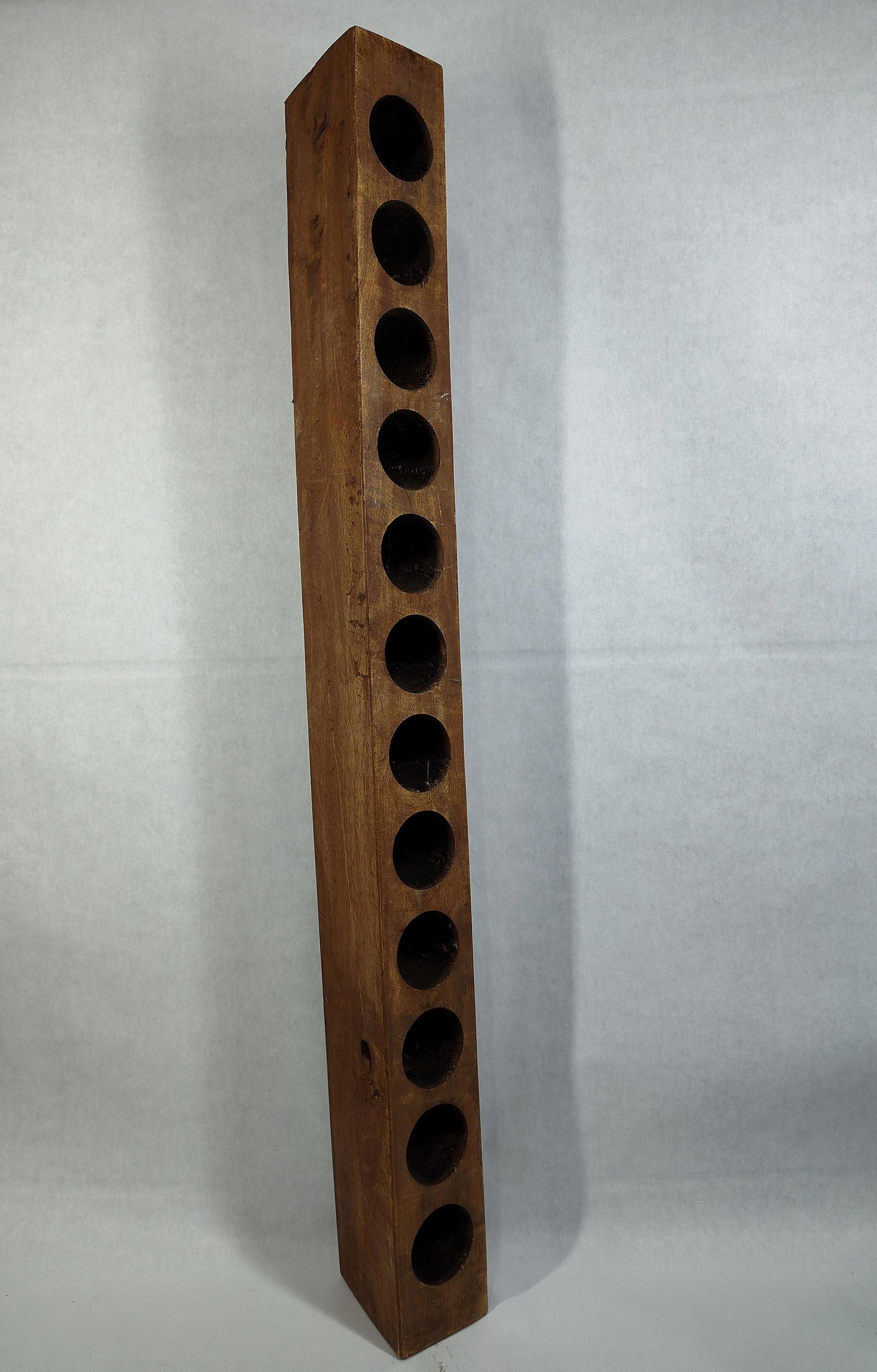 Twelve Hole Rustic Stained Wood Vertical Wine Rack: 38.5 inches long. A tall, vertical wine rack or bottle holder crafted from solid wood with a dark brown stained finish. The piece is constructed from a single rectangular timber beam featuring twelve