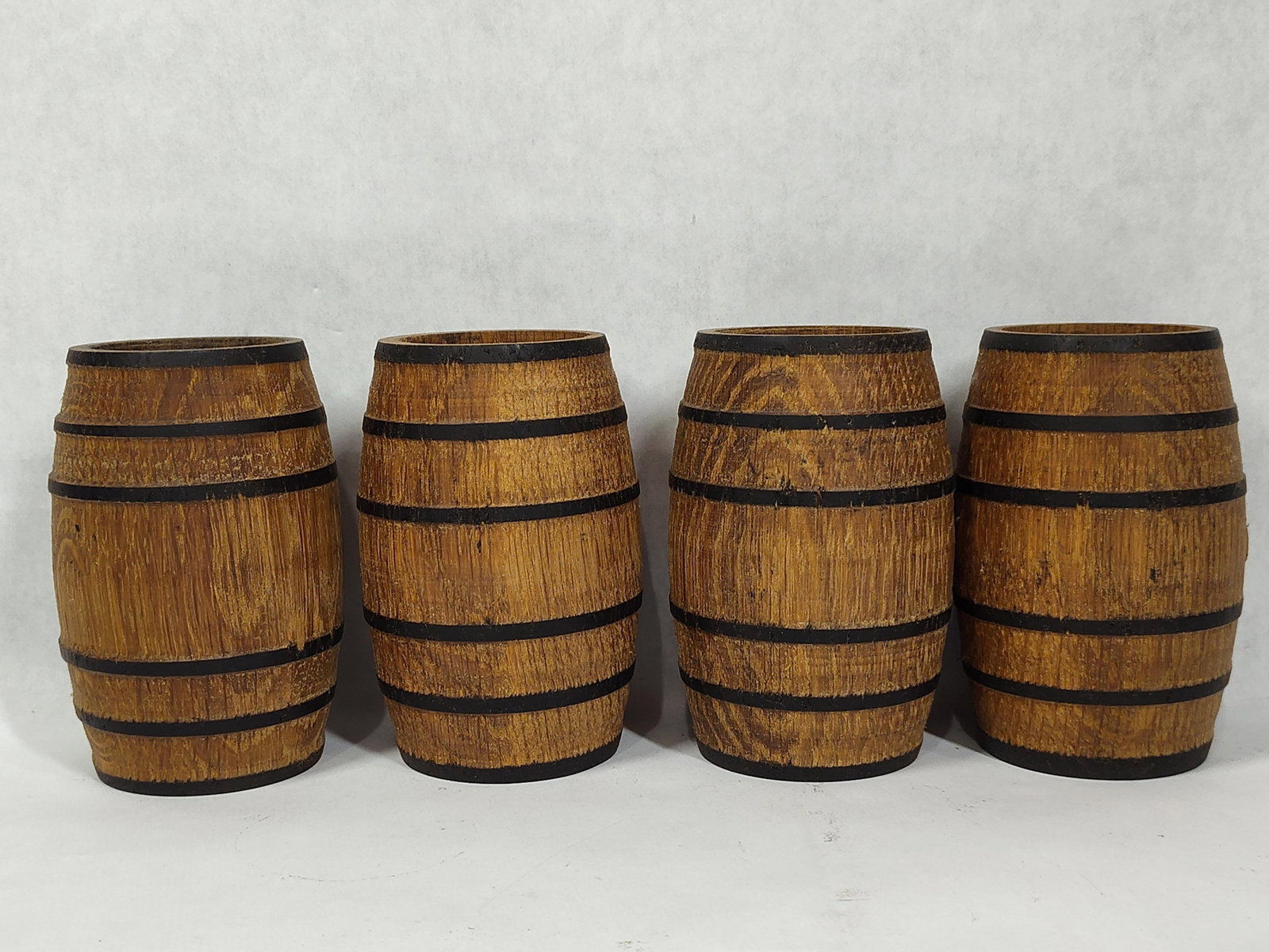 A Collection of Rustic Miniature Wooden Barrels: 4.5 inches tall. A collection of miniature wooden barrels of rustic design. Each vessel is constructed in a traditional coopered fashion using vertical wood staves. These staves are secured by four