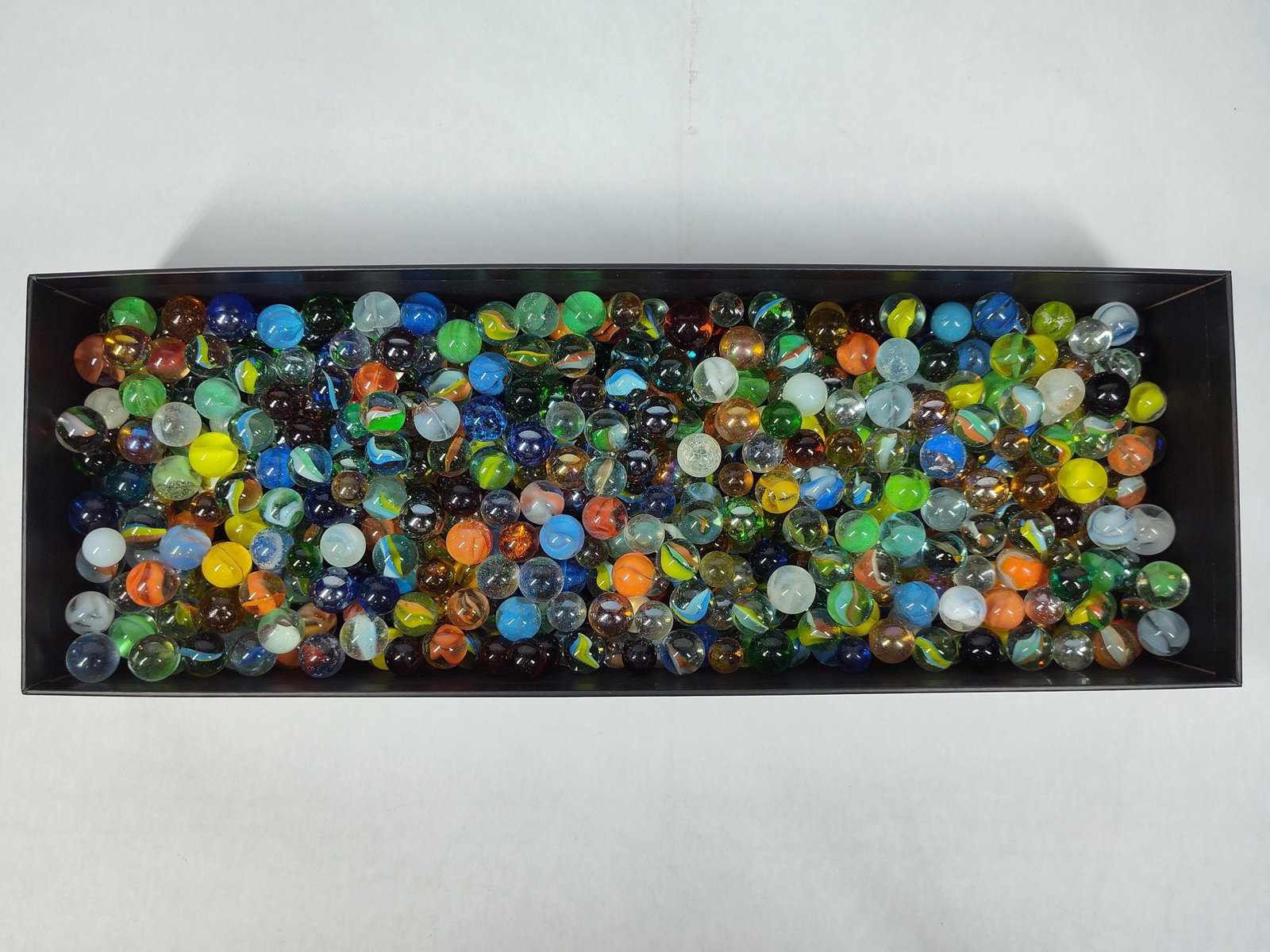 Assorted Glass Marbles: This lot consists of a collection of glass marbles in an array of styles, colors, and sizes. The assortment includes cat's eyes with multiple internal vanes, solid opaque marbles, transparent colored
