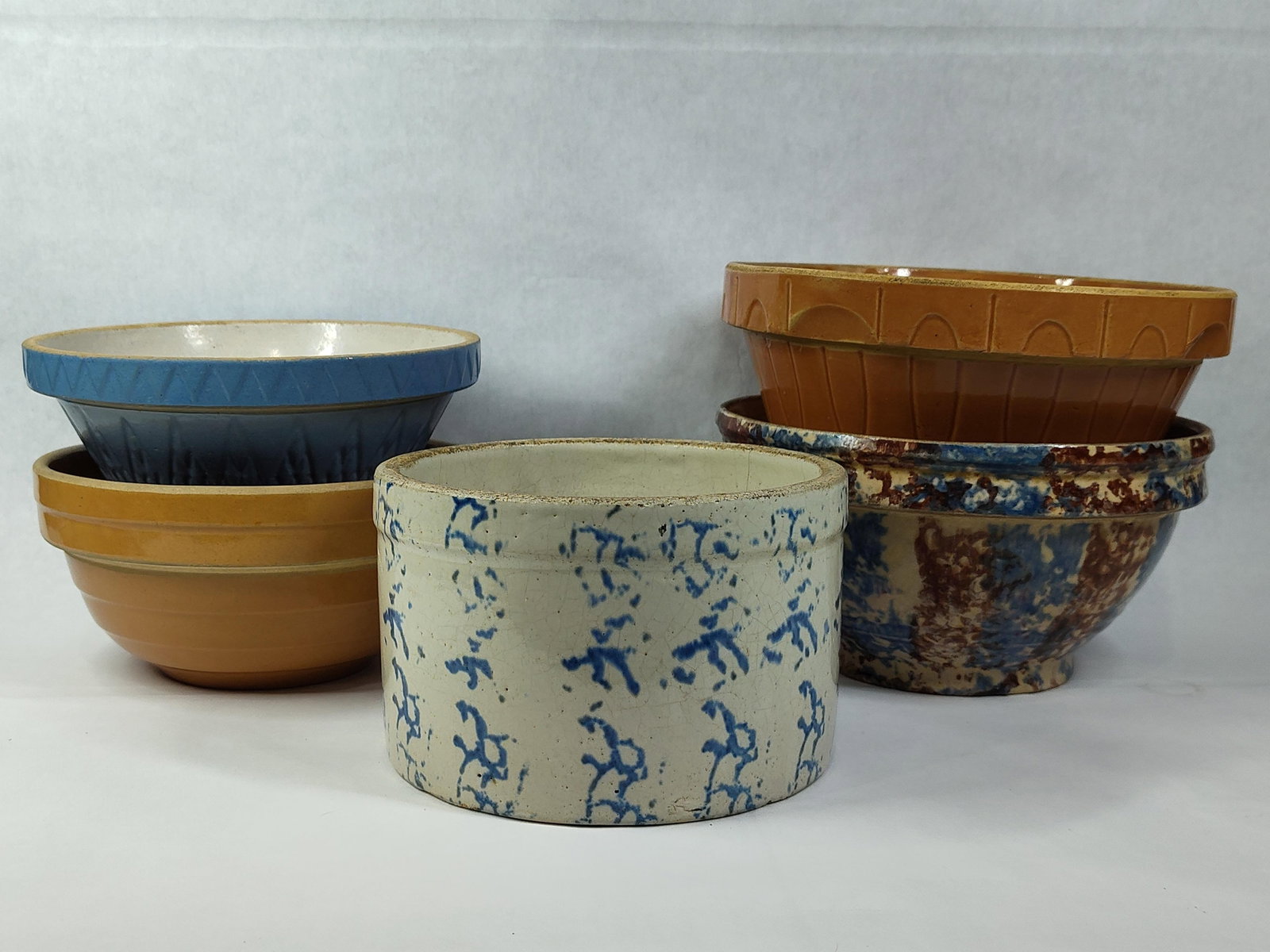 American Yellowware & Spongeware Bowls & Crock: This collection consists of five pieces of American utilitarian pottery, including a variety of mixing bowls and a storage vessel produced between the late 19th and mid-20th centuries. Included is a