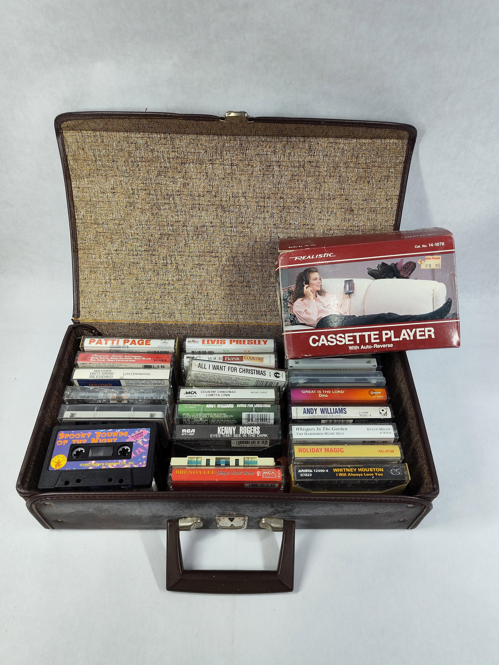 Realistic AM-FM Stereo Mate & Cassette Tapes: This lot features a Realistic AM-FM Stereo Mate portable cassette player, catalog number 14-1076. The unit is equipped with auto-reverse functionality and a Dolby System. It is presented in its