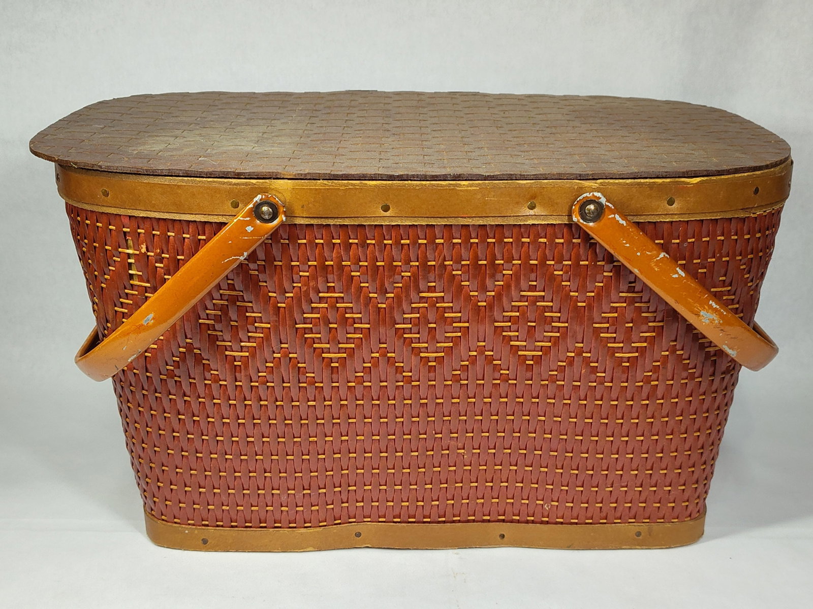 Red-Man Attributed Diamond Pattern Picnic Basket: Attributed to Red-Man Quality Baskets based on design consensus, this mid-century picnic basket features a reddish-brown woven body with a decorative diamond-weave pattern accented by natural-colored