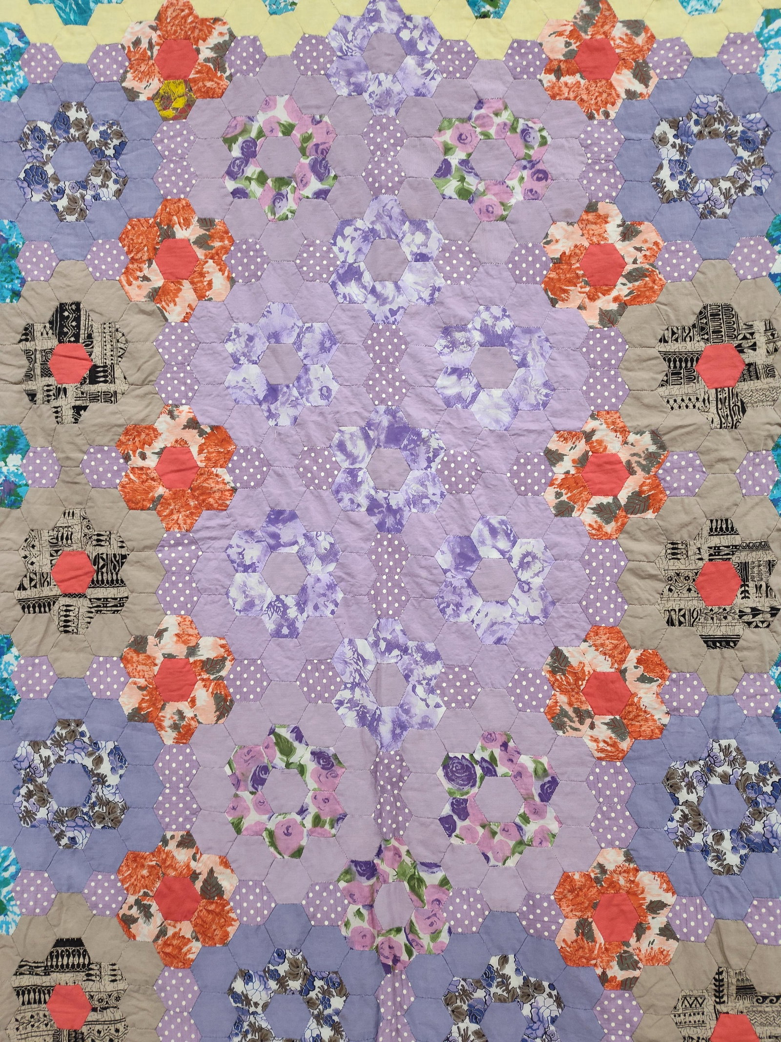 Grandmothers Flower Garden Cotton Quilt: A vintage cotton quilt featuring the traditional Grandmothers Flower Garden pattern. The quilt is hand-assembled using small hexagonal fabric patches to create a series of floral motifs. The central r