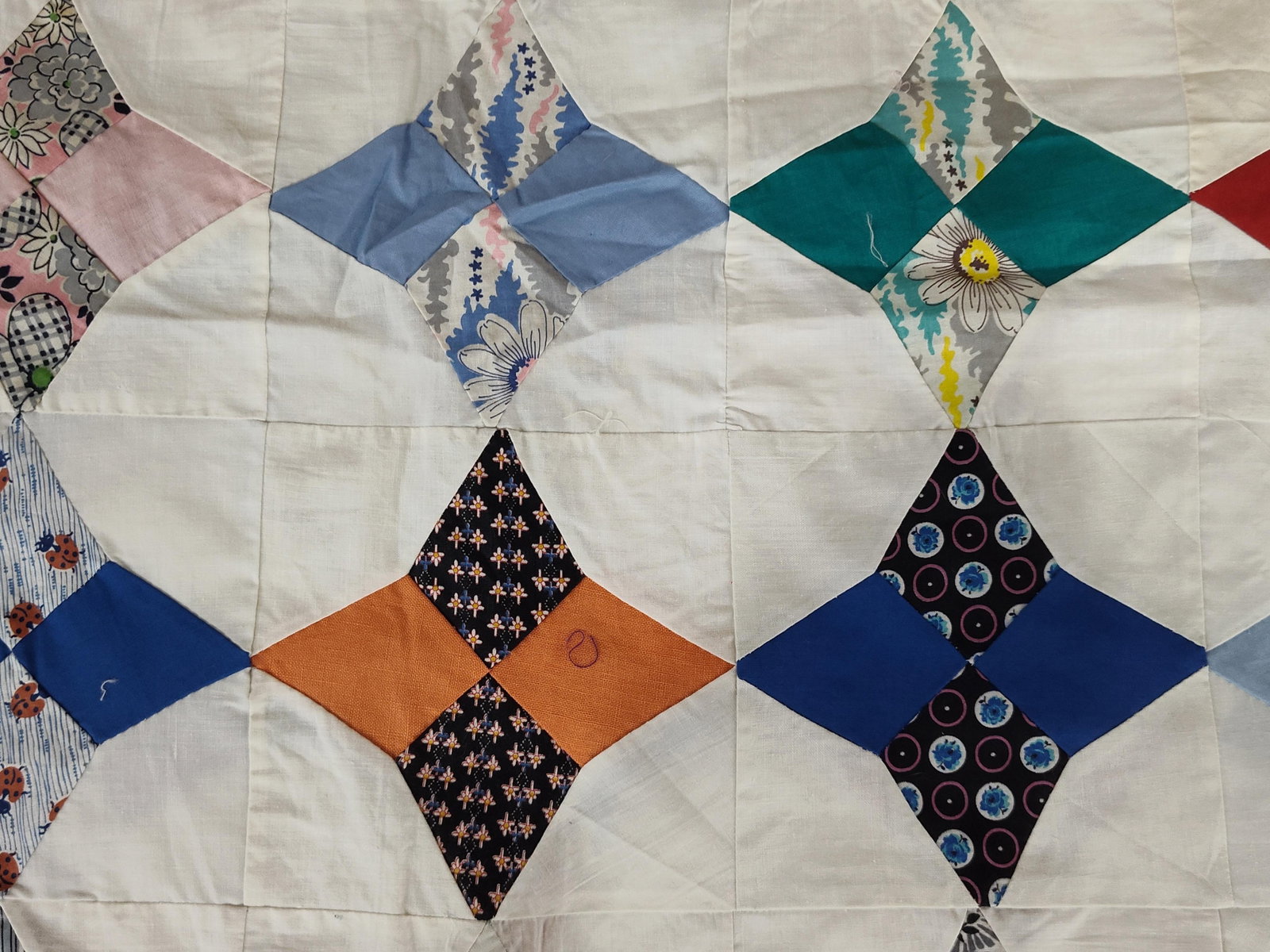 Mid-20th Century American Pieced Cotton Star Pattern Quilt Top: This item is an unfinished vintage quilt top, consisting of the pieced fabric layer only without batting, backing, or quilting. It is constructed from a variety of cotton fabrics featuring four-pointe