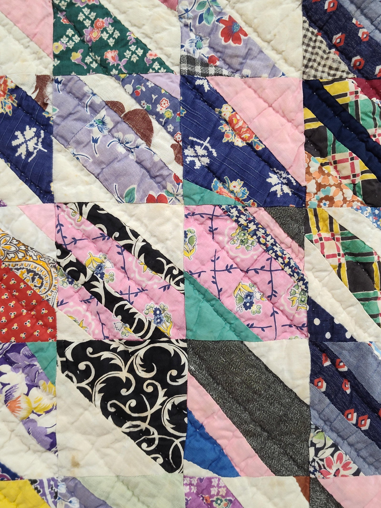 American Cotton String Patchwork Quilt, 20th C: This vintage American string patchwork quilt is constructed from numerous multicolored cotton and cotton-blend fabric strips pieced diagonally onto white or off-white foundation triangles. These