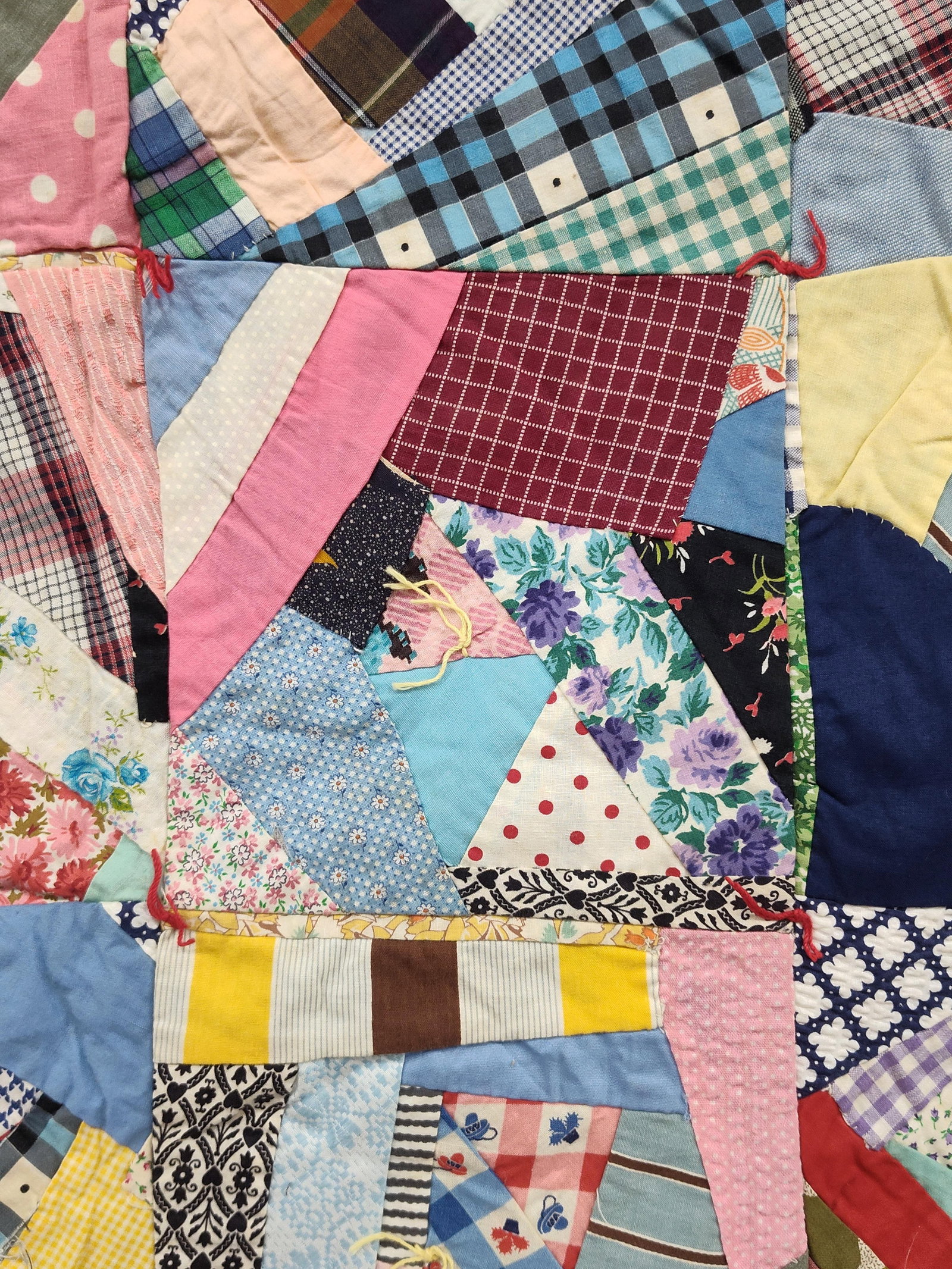 Handmade Patchwork Cotton Crazy Block Tied Quilt: This handmade scrap quilt is constructed from a grid of square blocks, with each block featuring an irregular crazy quilt arrangement of various fabric remnants. The top surface consists of a diverse 
