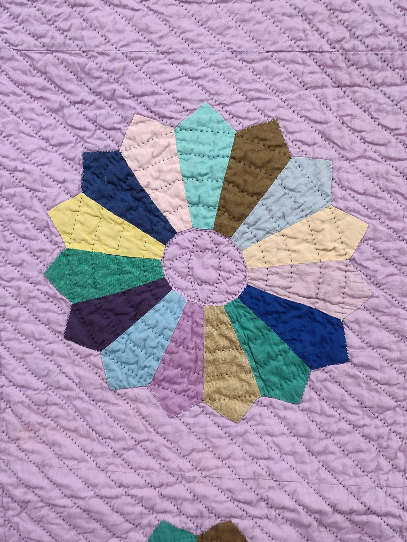 Hand-Quilted Dresden Plate Pattern Quilt: This textile is a vintage hand-quilted bedcovering featuring the traditional Dresden Plate pattern. The quilt is comprised of twenty individual blocks arranged in a four-by-five grid. Each block conta