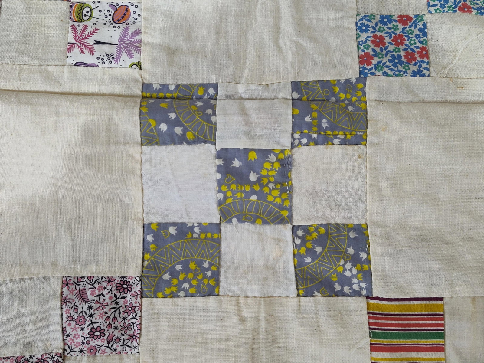 Mid-20th C. Hand-Pieced Nine Patch Quilt Top: This textile is a hand-pieced cotton quilt top featuring a Nine Patch pattern. The design utilizes alternating pieced blocks and large, solid cream cotton squares. The decorative blocks are constructe