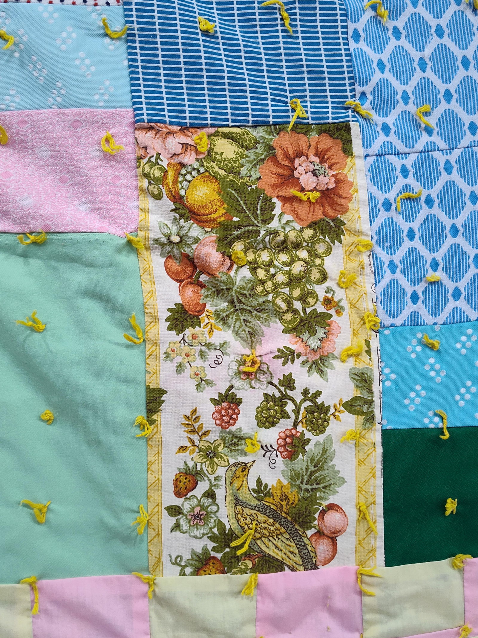 Pair Handmade Patchwork Tied Remnant Quilts: This lot features two vintage, handmade patchwork tied quilts constructed from an assortment of fabric remnants, including cotton and poly-cotton blends. The first quilt is characterized by large, irr