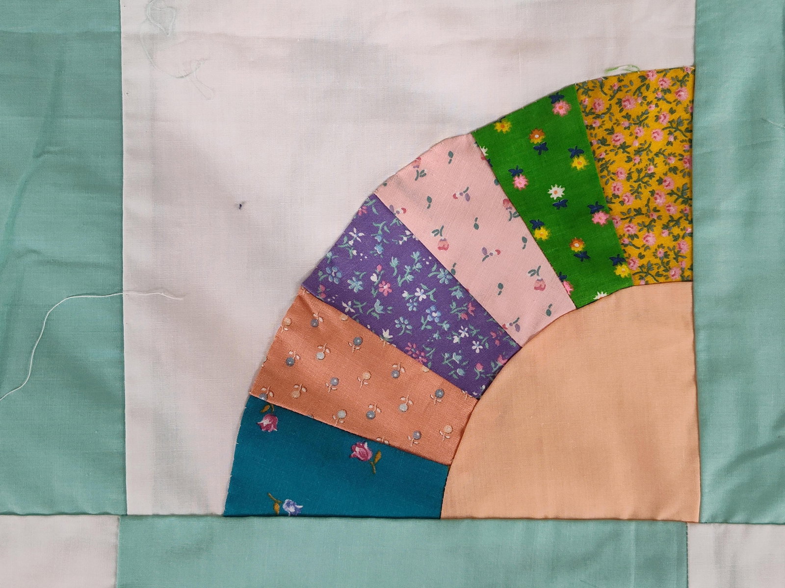 Grandmothers Fan Quilt Top: A vintage unfinished quilt top featuring the Grandmothers Fan pattern. The textile is composed of twenty square blocks arranged in a four-by-five grid. Each block displays a pieced fan motif in one co