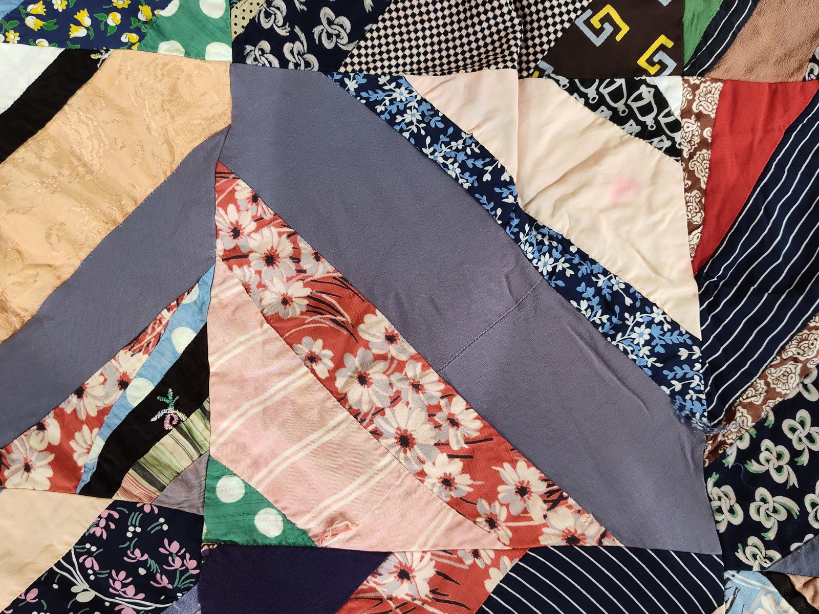 Mid-C. Hand-Pieced Scrappy Spiderweb String Quilt: A vintage hand-pieced scrap string quilt featuring a radiating spiderweb or starburst design. The quilt top is constructed from a diverse assortment of mid-century fabric remnants, including floral ca