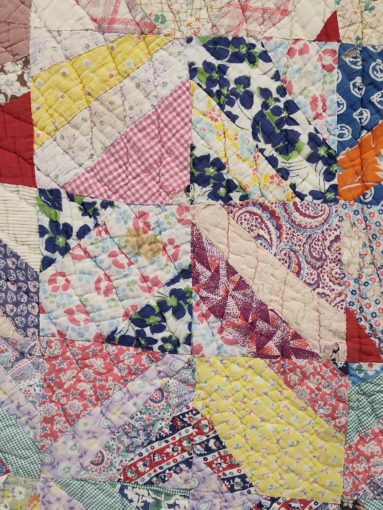 American Hand Quilted Feed Sack & Scrap Quilt: This mid-20th-century American scrap quilt is hand-quilted and features a variety of multi-colored cotton fabrics, including calicos, florals, ginghams, and novelty prints such as anchors. The constru