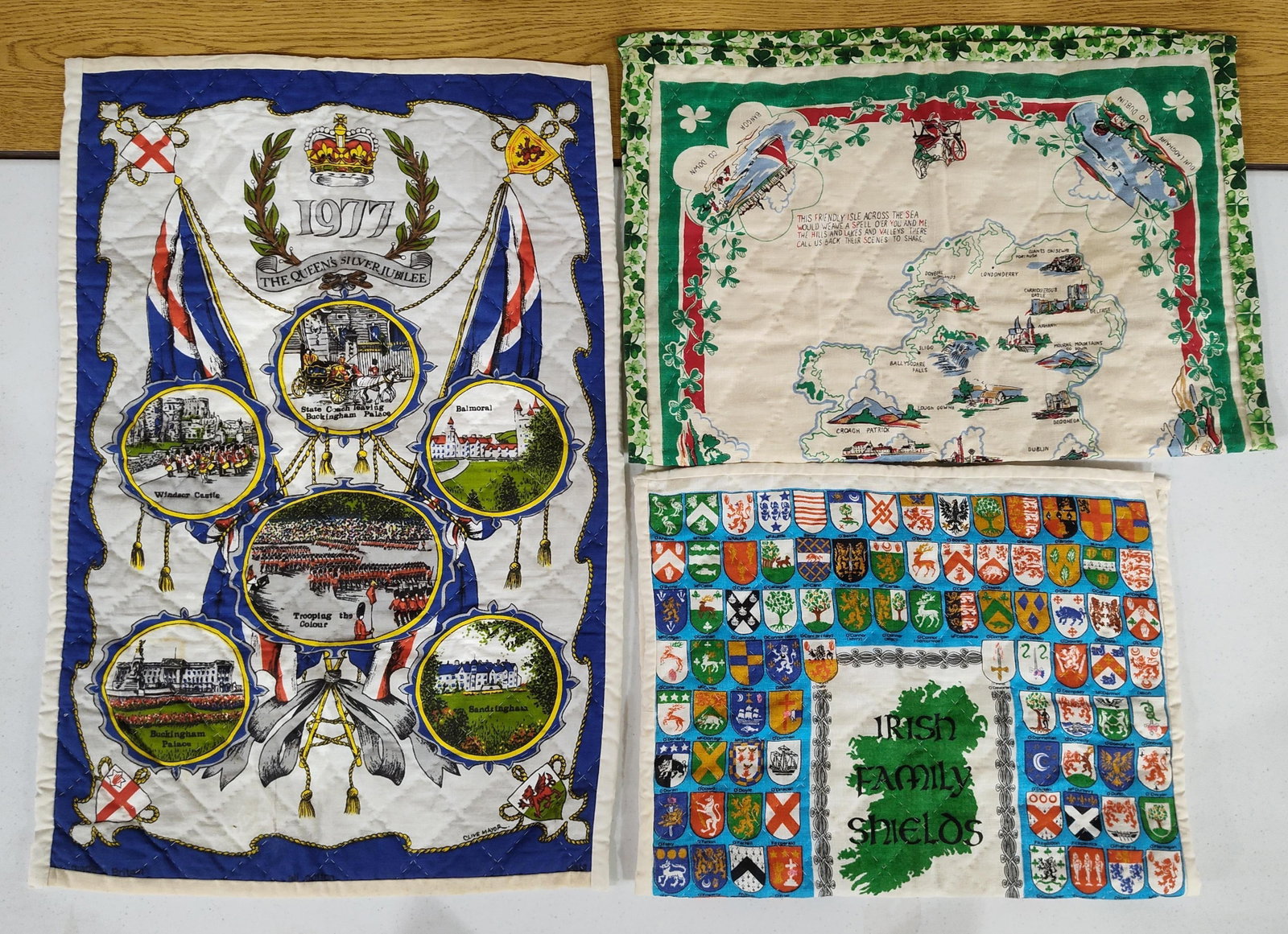 Trio Quilted Panels: QEII Jubilee & Irish: This lot features three vintage souvenir quilted fabric panels, each finished with a diamond-stitched pattern and white perimeter binding. The first panel commemorates the 1977 Silver Jubilee of Queen