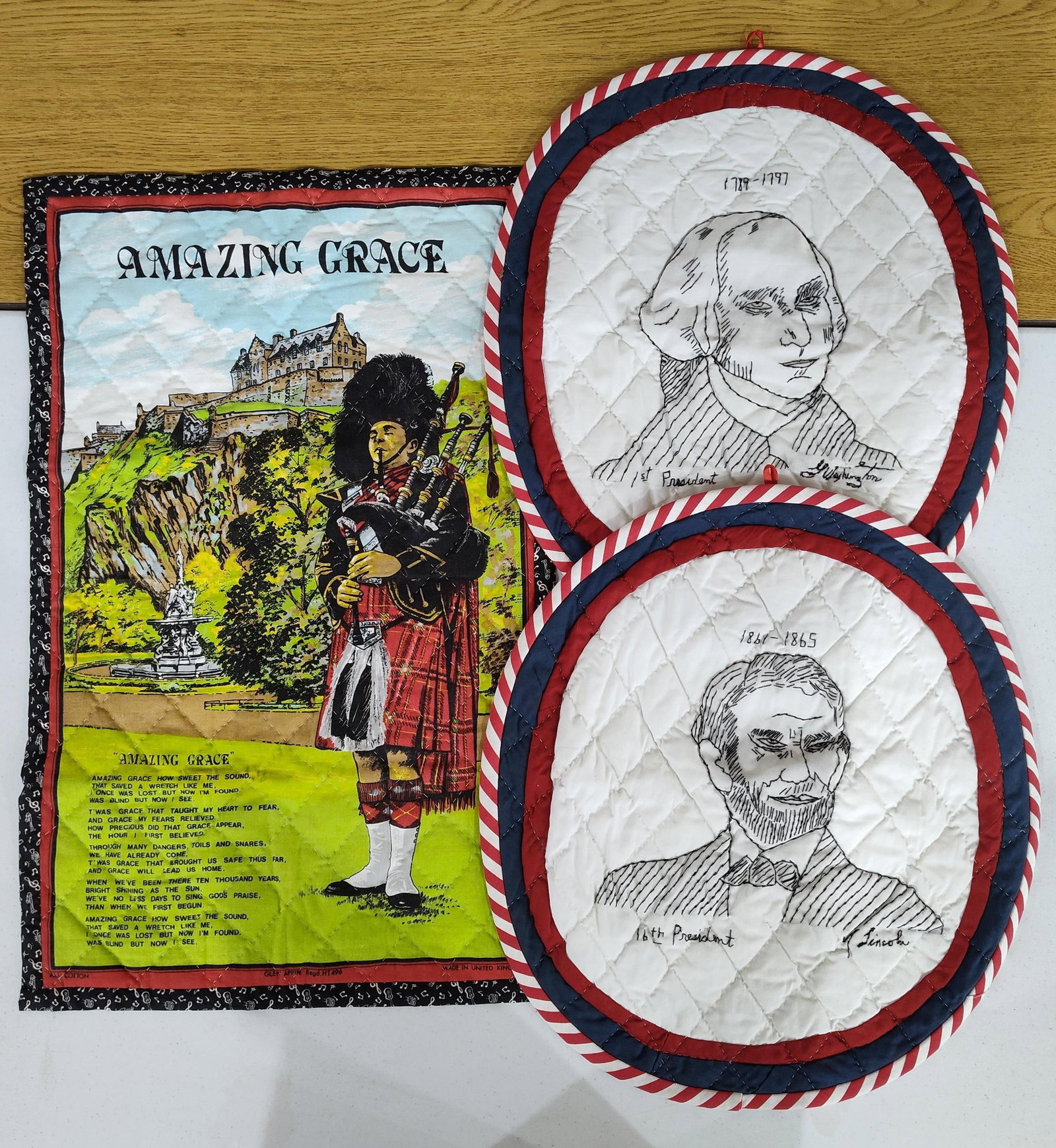 Glen Appin Hanging & Presidential Pot Holders: This lot consists of three quilted textile items. The first is a rectangular quilted cotton wall hanging produced by Glen Appin of Scotland. The panel features a printed illustration of a bagpiper in