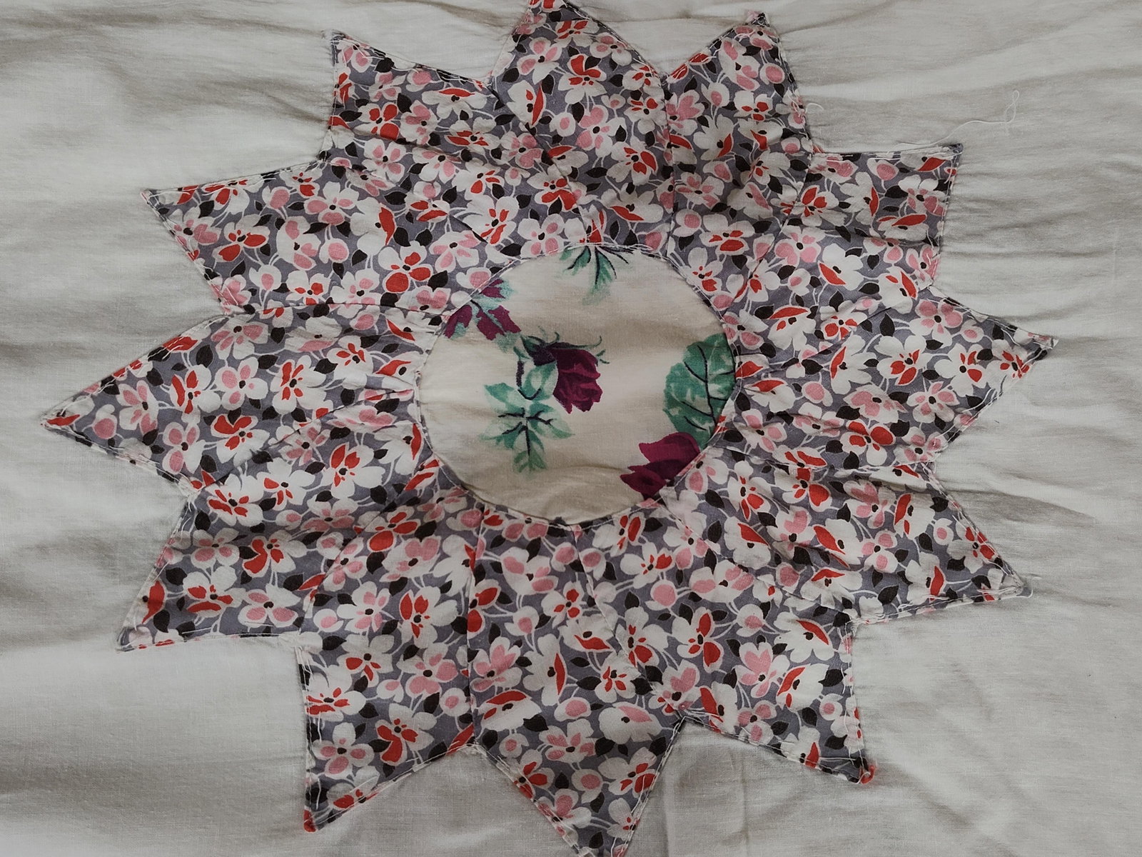 Hand Appliqued Sunburst Pattern Cotton Quilt Top: This is a vintage hand-appliqued cotton quilt top featuring multiple Sunburst or Dresden Plate motifs on a pieced white cotton ground. Each star-shaped motif is constructed from multiple pointed