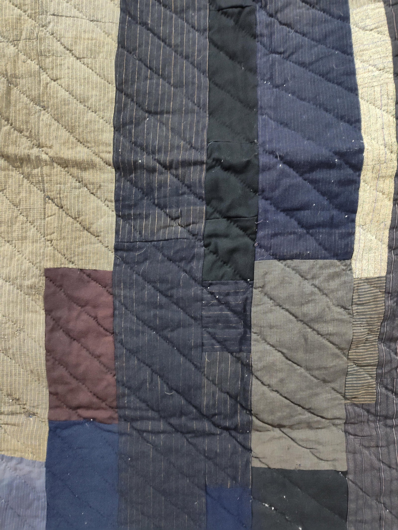 North American Improvisational Strip Utility Quilt: This hand-quilted utility quilt is constructed in an improvisational strip-pieced style, often referred to as a hired man quilt. The top is composed of vertical columns of scrap fabrics in a dark pale