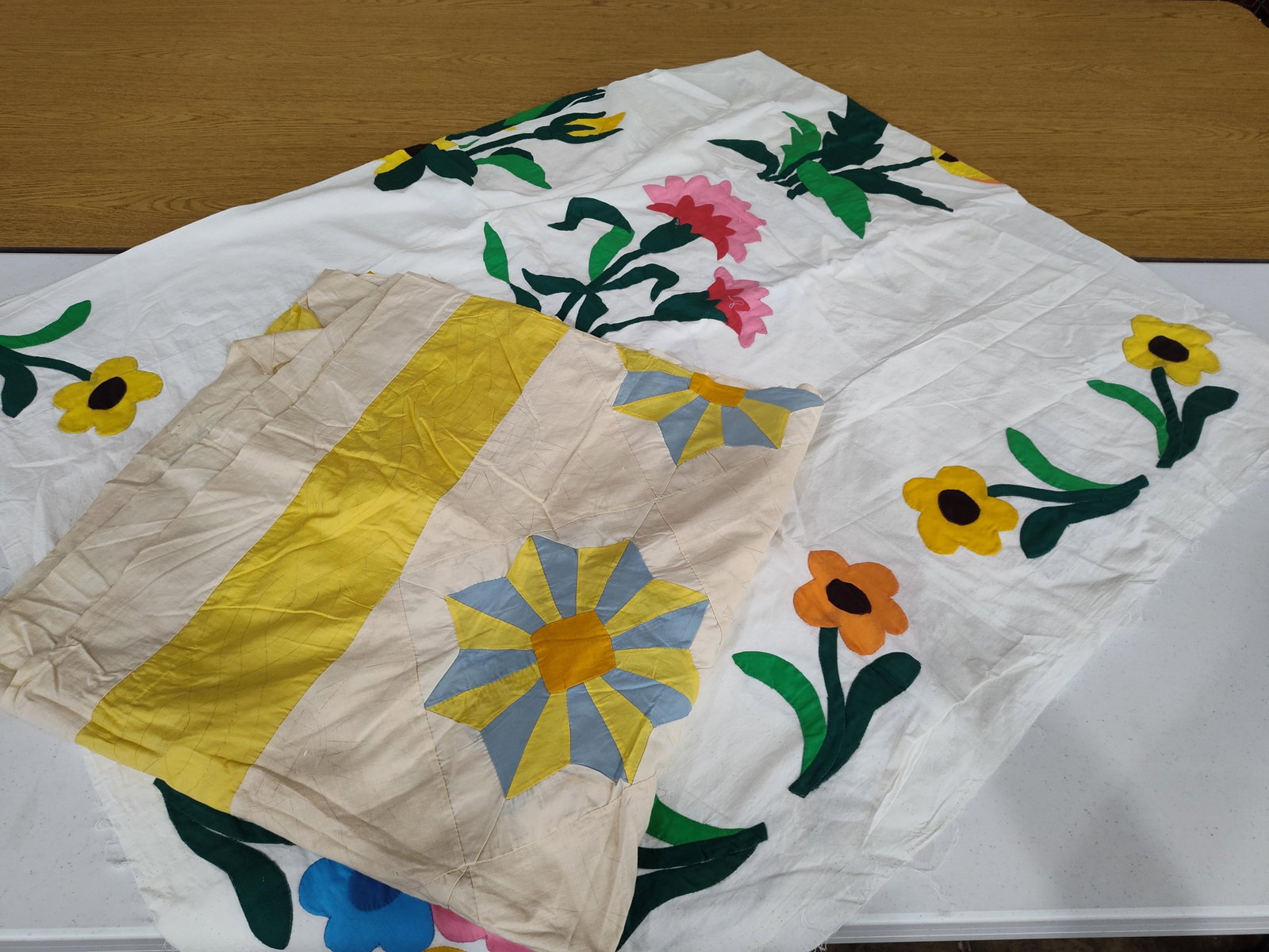 Pair Mid-20th C. Unfinished Cotton Quilt Tops: This lot consists of two unfinished cotton quilt tops dating to the mid-20th century, likely between 1930 and 1940. The first quilt top features a white cotton ground with hand-appliqued floral