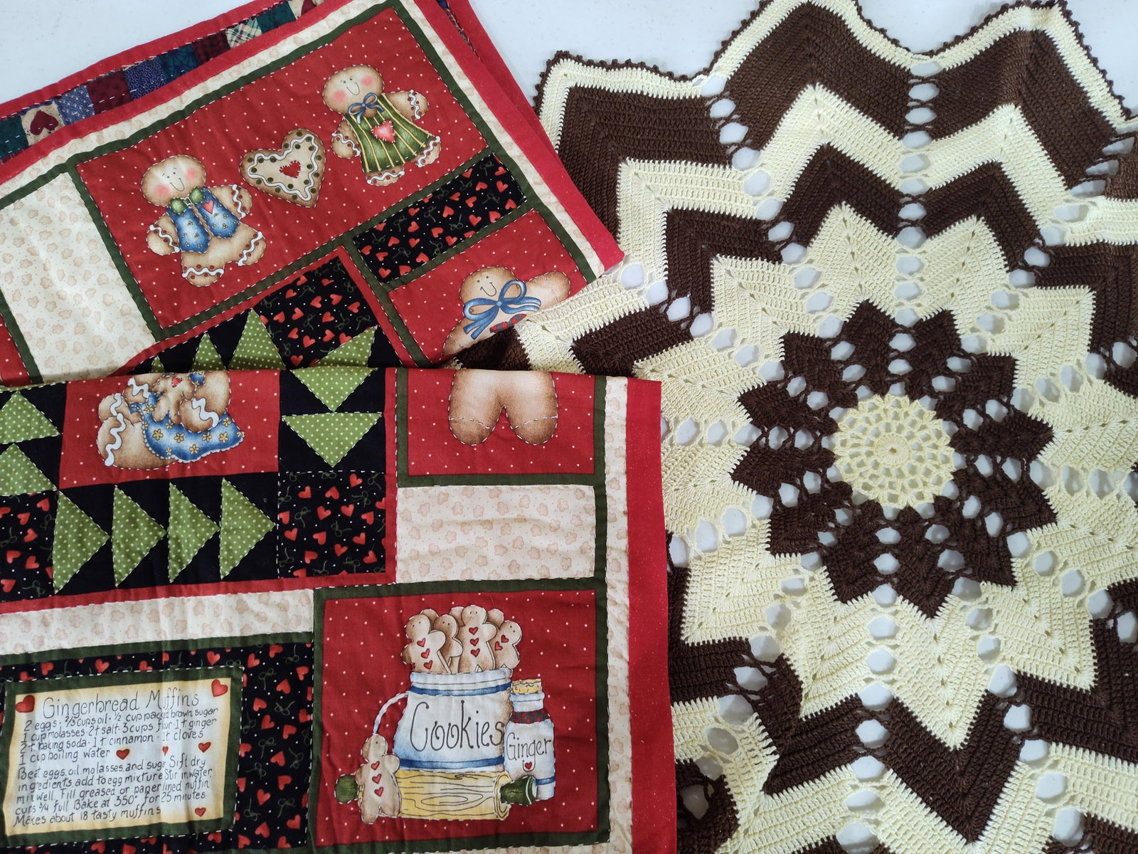 Pair Gingerbread Placemats & Crocheted Star Doily: This collection includes three household textile items: two matching reversible quilted placemats and a large circular crocheted doily. The placemats are constructed from cotton fabric with interior b