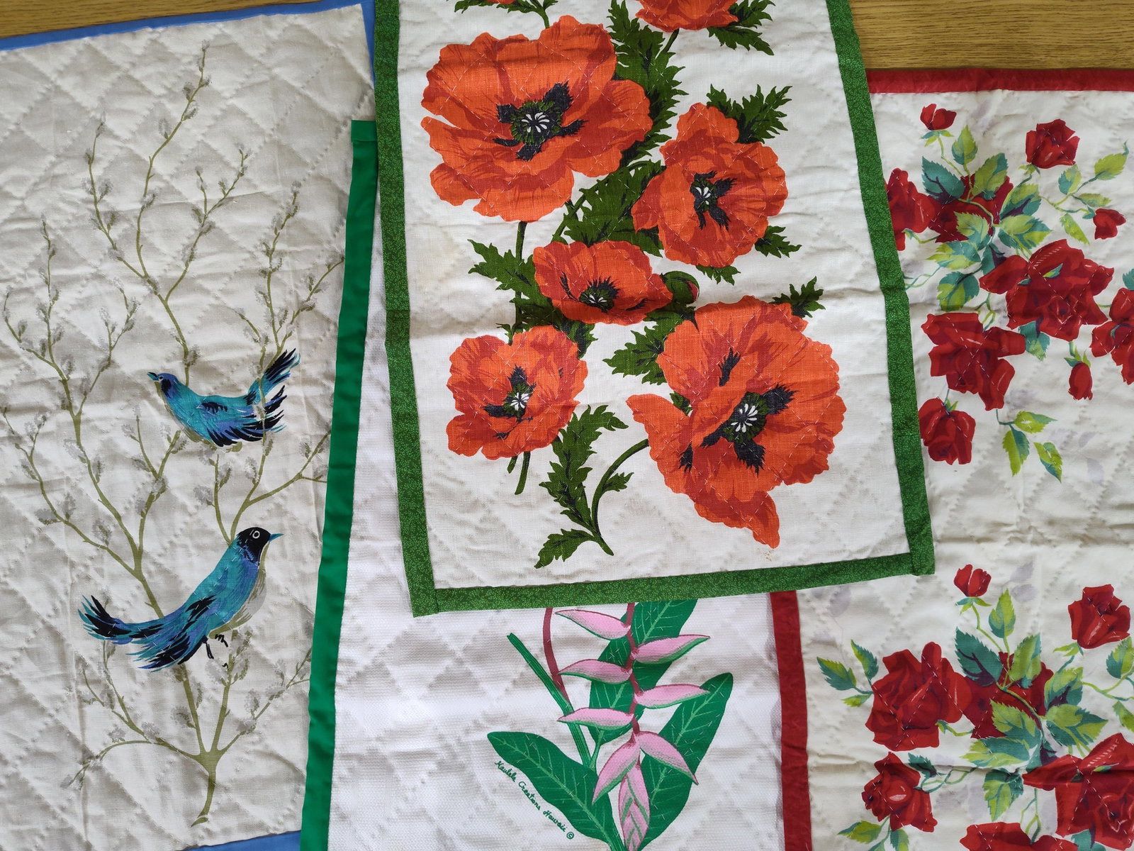 Kaulele Creations Hawaii Botanical Quilted Panels: A collection of four quilted fabric panels or runners, each featuring distinct botanical or ornithological prints. The panels are constructed with diamond-patterned machine quilting on the face and fi