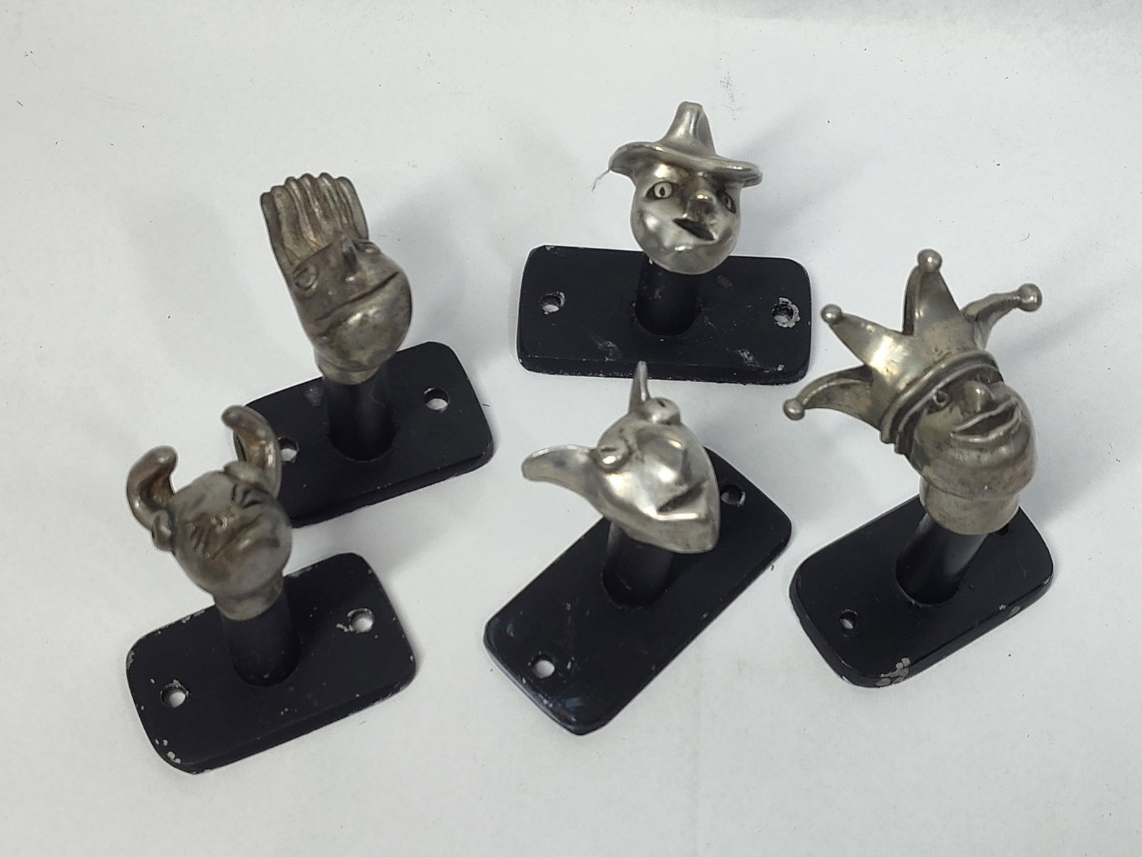 Set 5 Figural Metal Wall Hooks: A set of five figural wall hooks featuring whimsical character heads. Each hook is constructed with a cast white metal head, featuring hand-finished details and a dull silver-toned patina and are