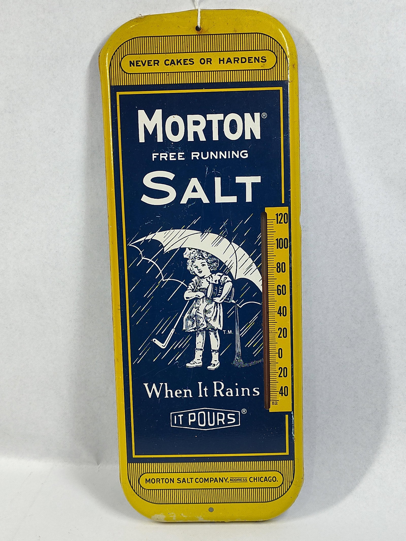 Morton Salt Metal Thermometer Sign: 6x16 A vintage advertising thermometer for the Morton Salt Company. The piece is constructed from stamped metal with a painted finish and features the iconic Morton Salt Girl illustration in blue and