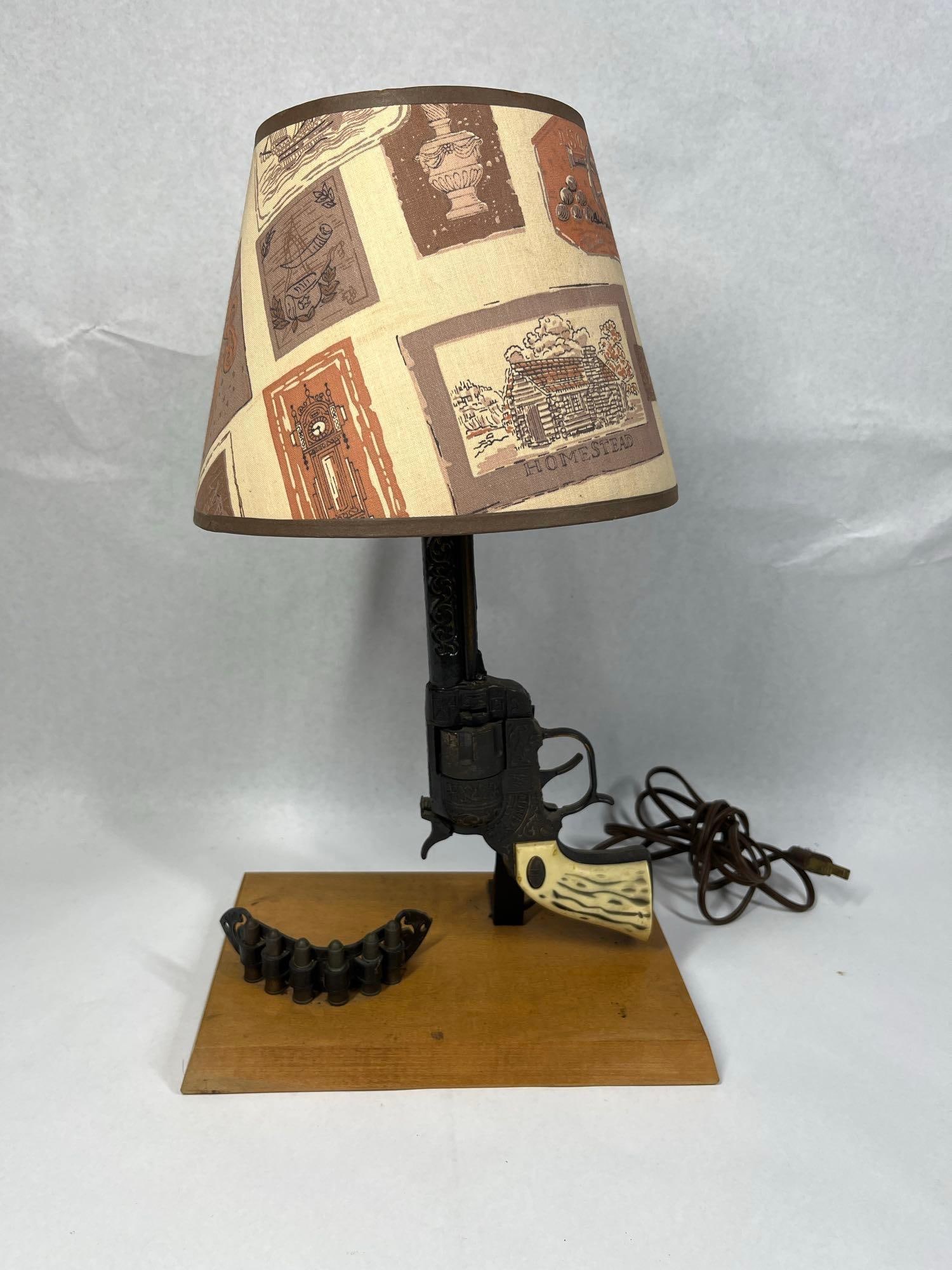 Western Six Shooter & Texas Ranger Lamp: This vintage table lamp features a replica single-action revolver serving as the central support column, mounted on a rectangular wooden base. The revolver body is constructed of cast metal with decor