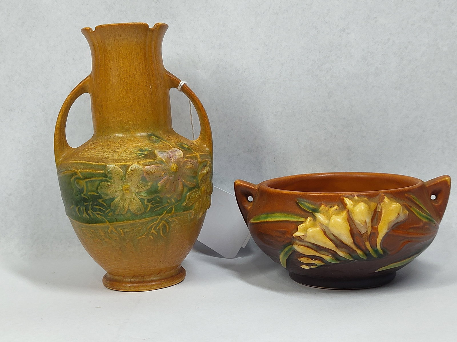 Roseville Freesia & Weller Dogwood Pots: 2.5 and 6in tall. This lot features two pieces of mid-century American art pottery with relief-molded floral motifs. The first item is a Roseville Pottery bowl in the Freesia pattern, introduced in 19