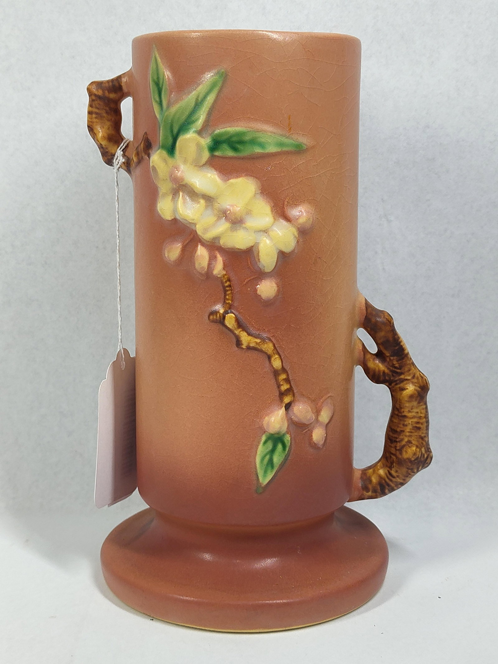 Roseville Apple Blossom Vase 387-7: 9.5in tall An American art pottery earthenware vase produced by Roseville Pottery in the Apple Blossom pattern, introduced circa 1948. The vase features a tall, cylindrical body with two offset, rusti