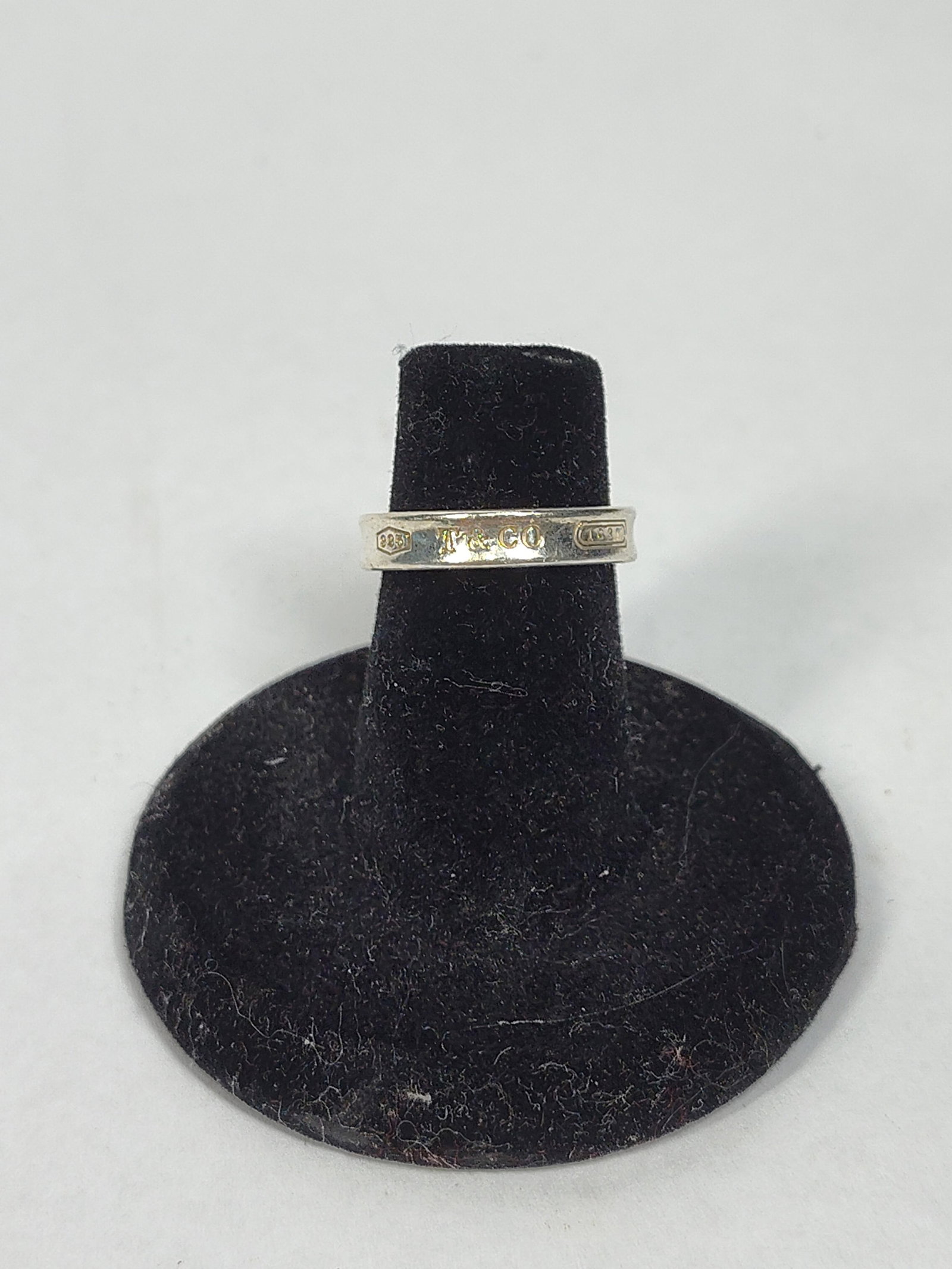 Tiffany & Co. 1837 Sterling Ring: A sterling silver band ring from the Tiffany and Co. 1837 collection. The band features a signature concave profile. The exterior of the ring is stamped with three distinct marks: a pentagonal shield 