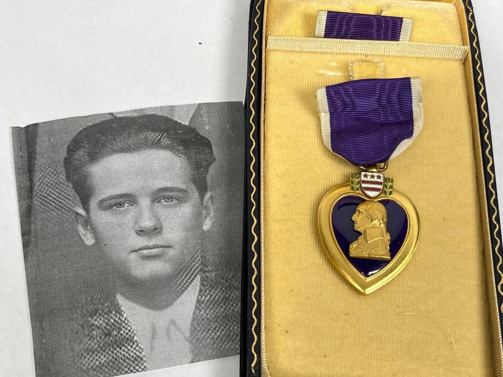 WWII United States Named Purple Heart Medal in Presentation Case with Photograph: This lot features a World War II-era United States Purple Heart medal officially engraved to Ralph M. Adams. The medal obverse consists of a heart-shaped medal with a purple enameled center featuring 
