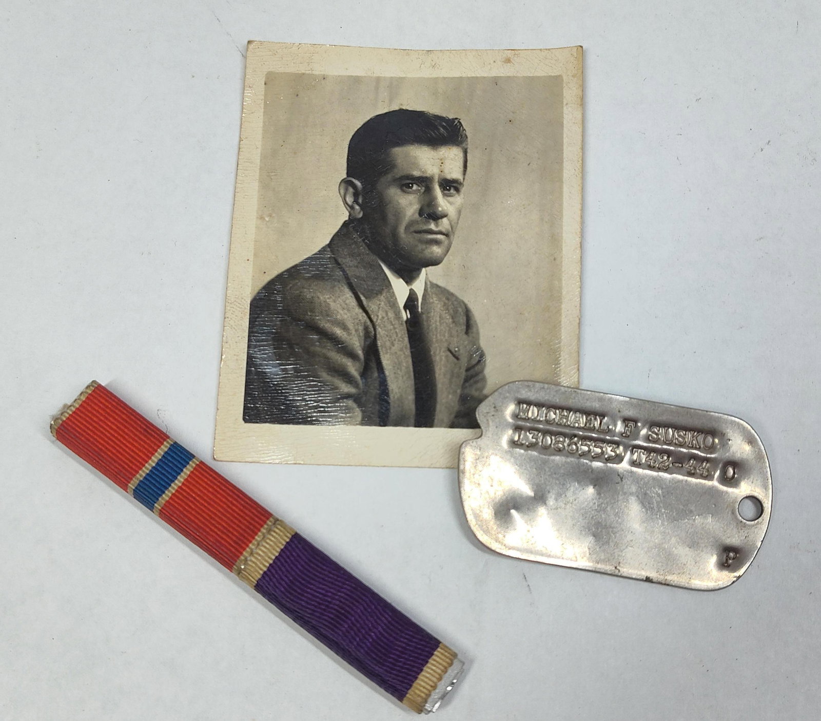 Identified WWII US Army Michael F. Susko Purple Heart and Bronze Star Grouping: A collection of identified World War II era United States Army memorabilia belonging to Michael F. Susko. The grouping includes a single M1940 pattern notched identification tag. The tag features debo