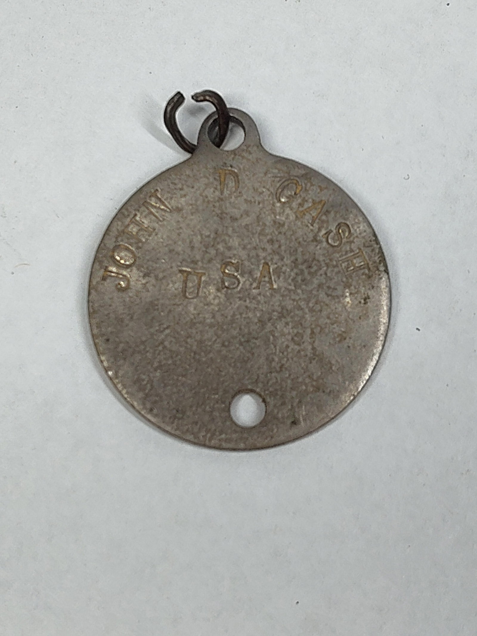 WWI-Era US Army Model 1916 Circular Identification Tag for John D. Cash: A United States Army Model 1916 circular identification tag, commonly known as a dog tag. The tag is constructed from a non-magnetic metal, likely aluminum or monel, and features an integral suspensio