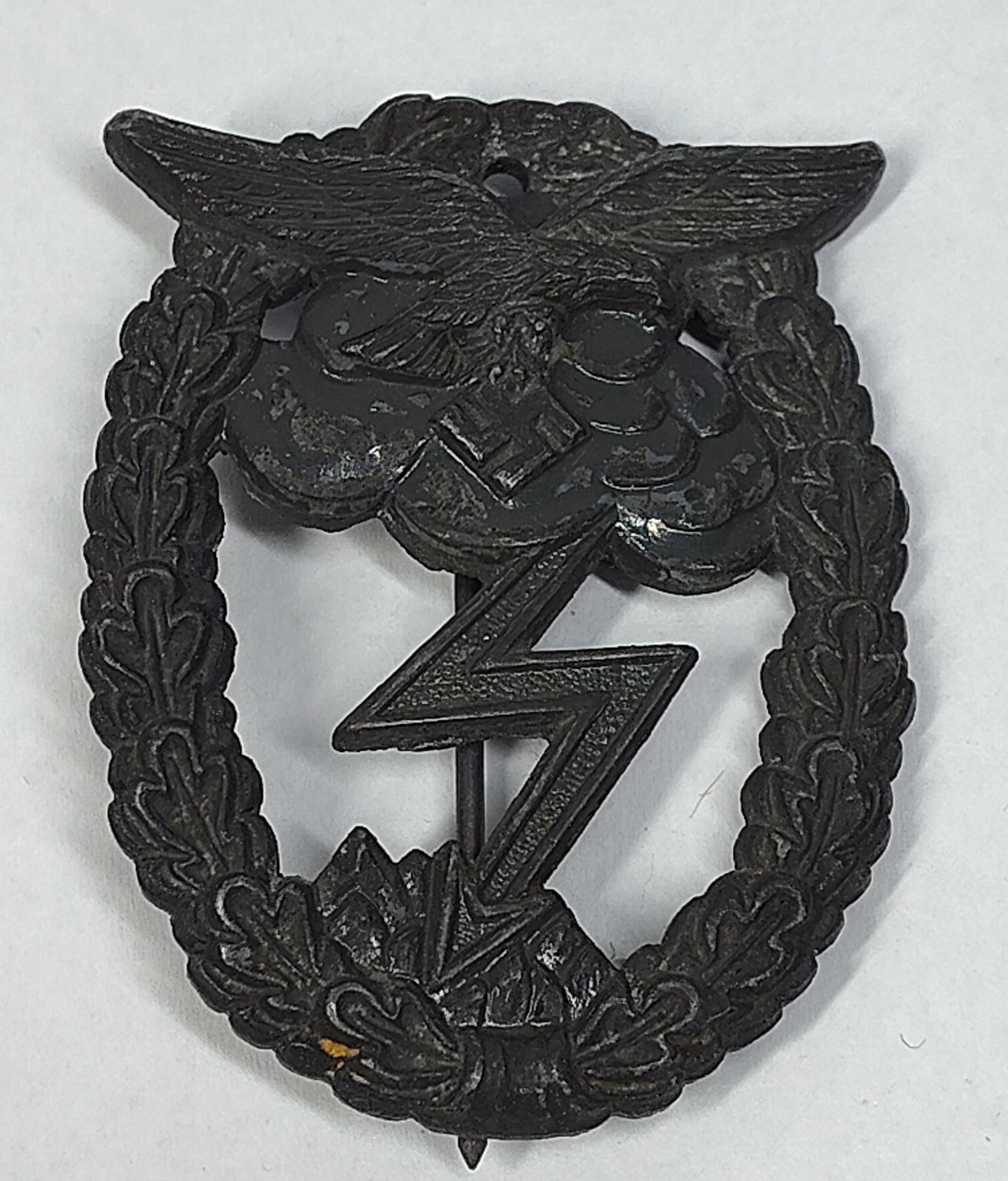 WWII German Luftwaffe Ground Assault Badge: This is a World War II German Luftwaffe Ground Assault Badge, known as the Erdkampfabzeichen der Luftwaffe. The design features an oval wreath of oak leaves tied with a ribbon at the base. Centered wi