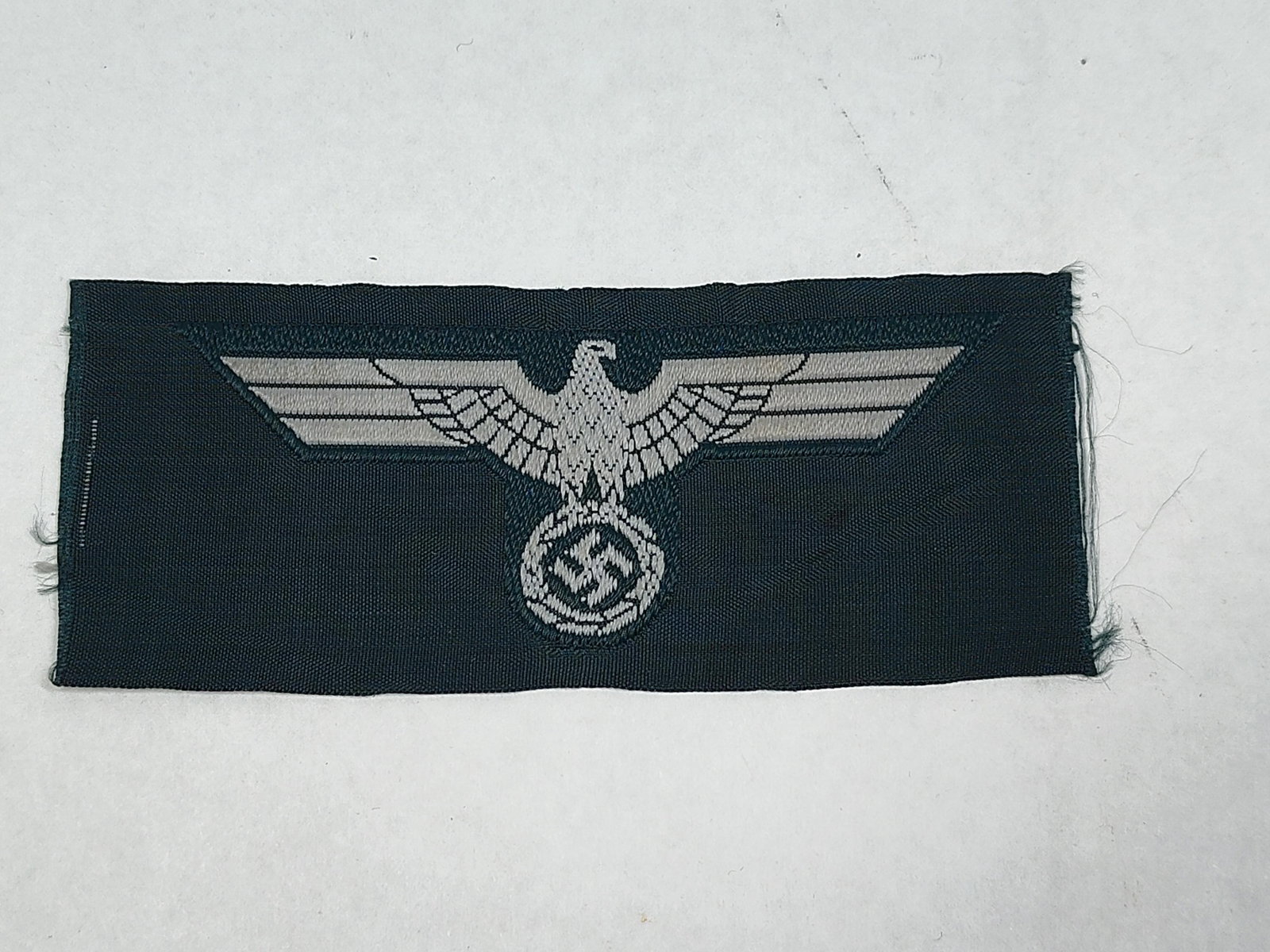WWII German Heer Panzer Enlisted Man Machine-Woven Breast Eagle: A World War II German Army (Heer) Panzer enlisted man's breast eagle (Hoheitsabzeichen). The insignia is machine-woven using silver-grey rayon thread on a black woven backing. This specific color