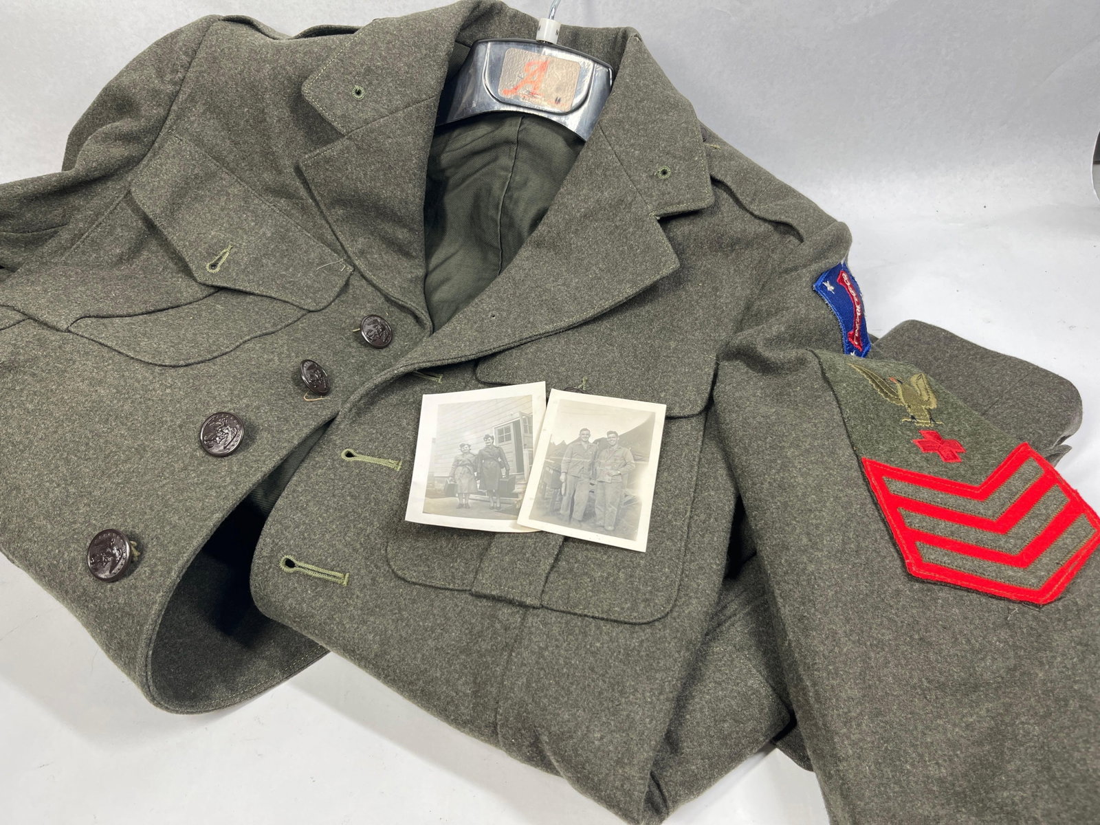 WWII USMC Service Jacket with 1st Marine Division Guadalcanal Patch and Navy Hospital Corpsman: A World War II era United States Marine Corps forest green wool service jacket with associated insignia and photographs. The garment features a four-button front closure and four exterior pleated