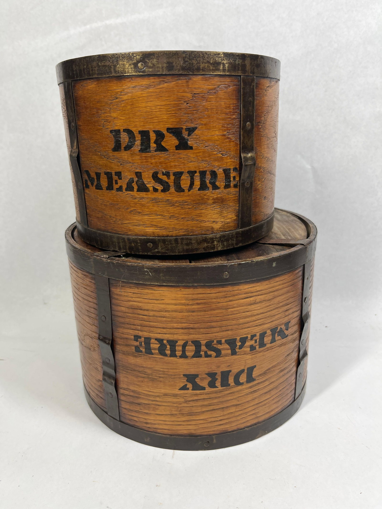 Pair Antique Oak Bentwood Dry Measures: 6.5 and 8.5 dia. A pair of antique wooden dry measures of graduated sizes, likely dating to the late 19th or early 20th century. These vessels feature a cylindrical bentwood construction, with the