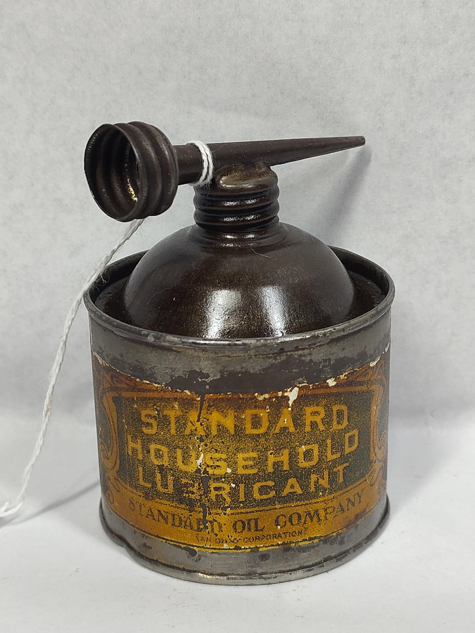 Standard Oil Household Lubricant Oiler: A vintage household lubricant oiler manufactured by the Standard Oil Company (An Ohio Corporation). The piece is constructed from tin-plated steel and features a cylindrical reservoir with a domed