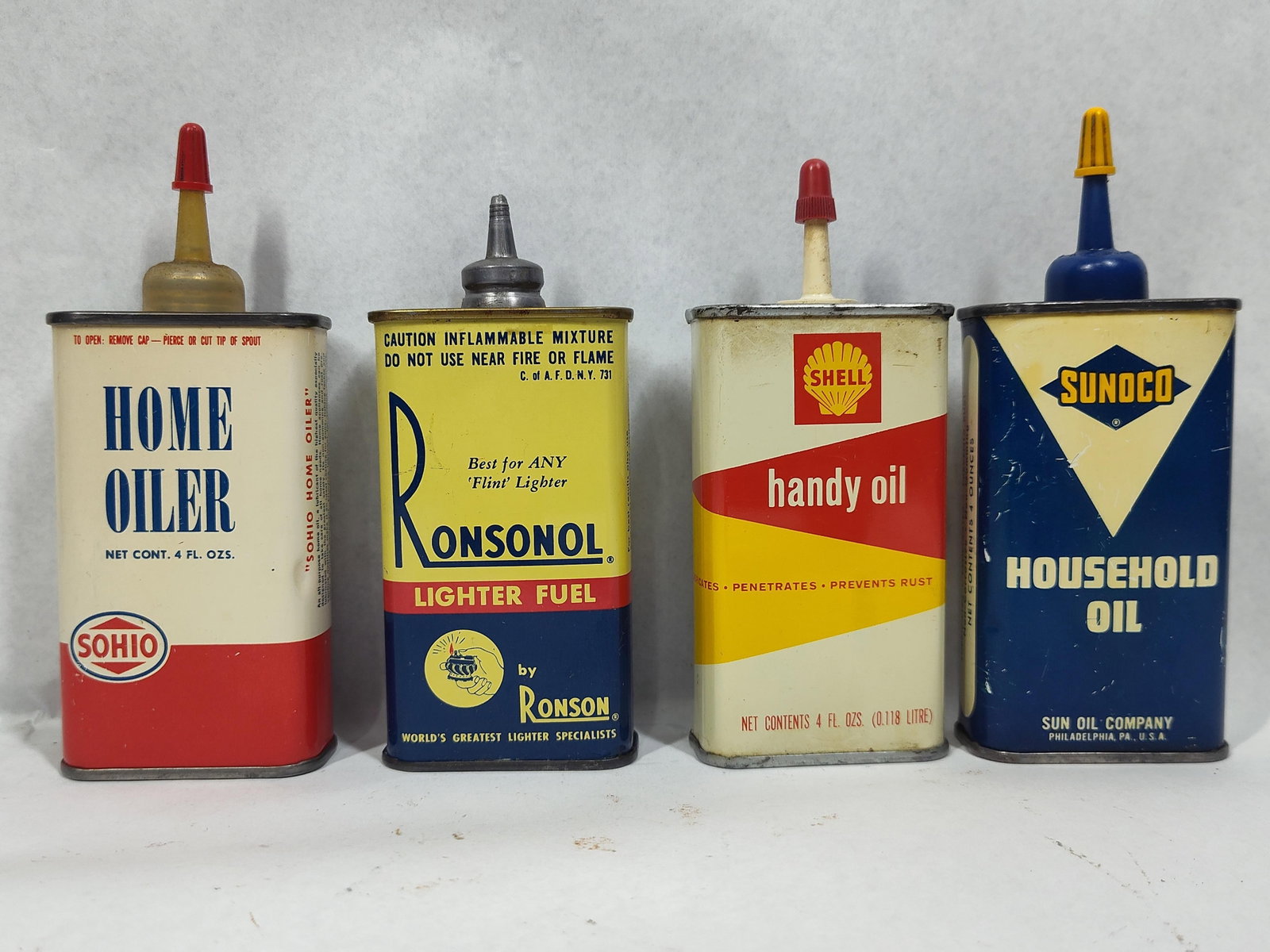 4 Sohio Shell Sunoco Ronsonol Oil Tins: A group of four vintage lithographed tin lubricant and fuel containers featuring advertising for Sohio, Shell, Sunoco, and Ronsonol. Each container has a stated capacity of 4 fluid ounces. The Sohio H