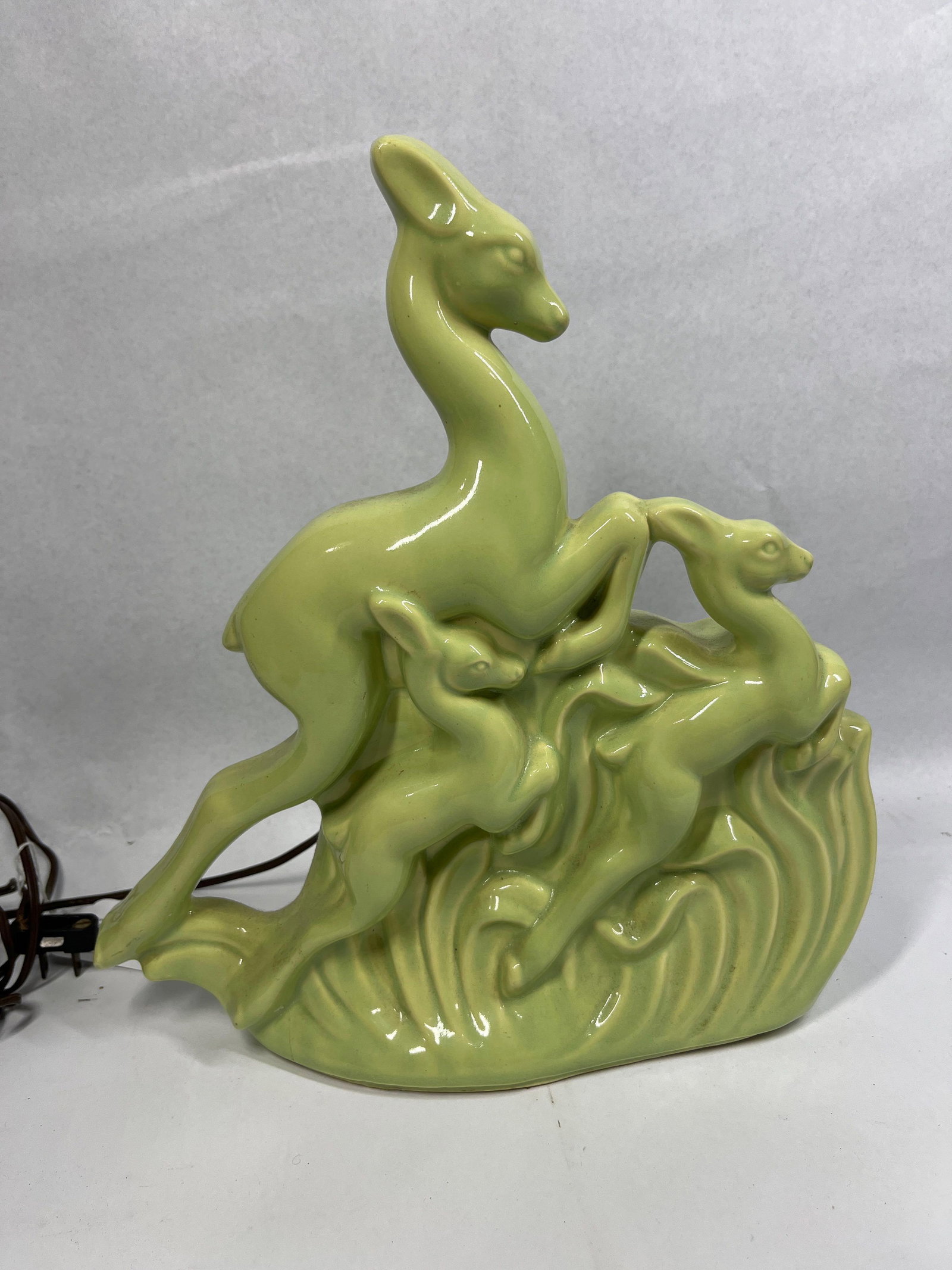 Chartreuse Ceramic Leaping Deer TV Lamp: 12x12 This mid-century modern ceramic TV lamp is designed as a sculptural group of leaping deer, a form characteristic of 1950s decorative lighting. The composition features three stylized deer,