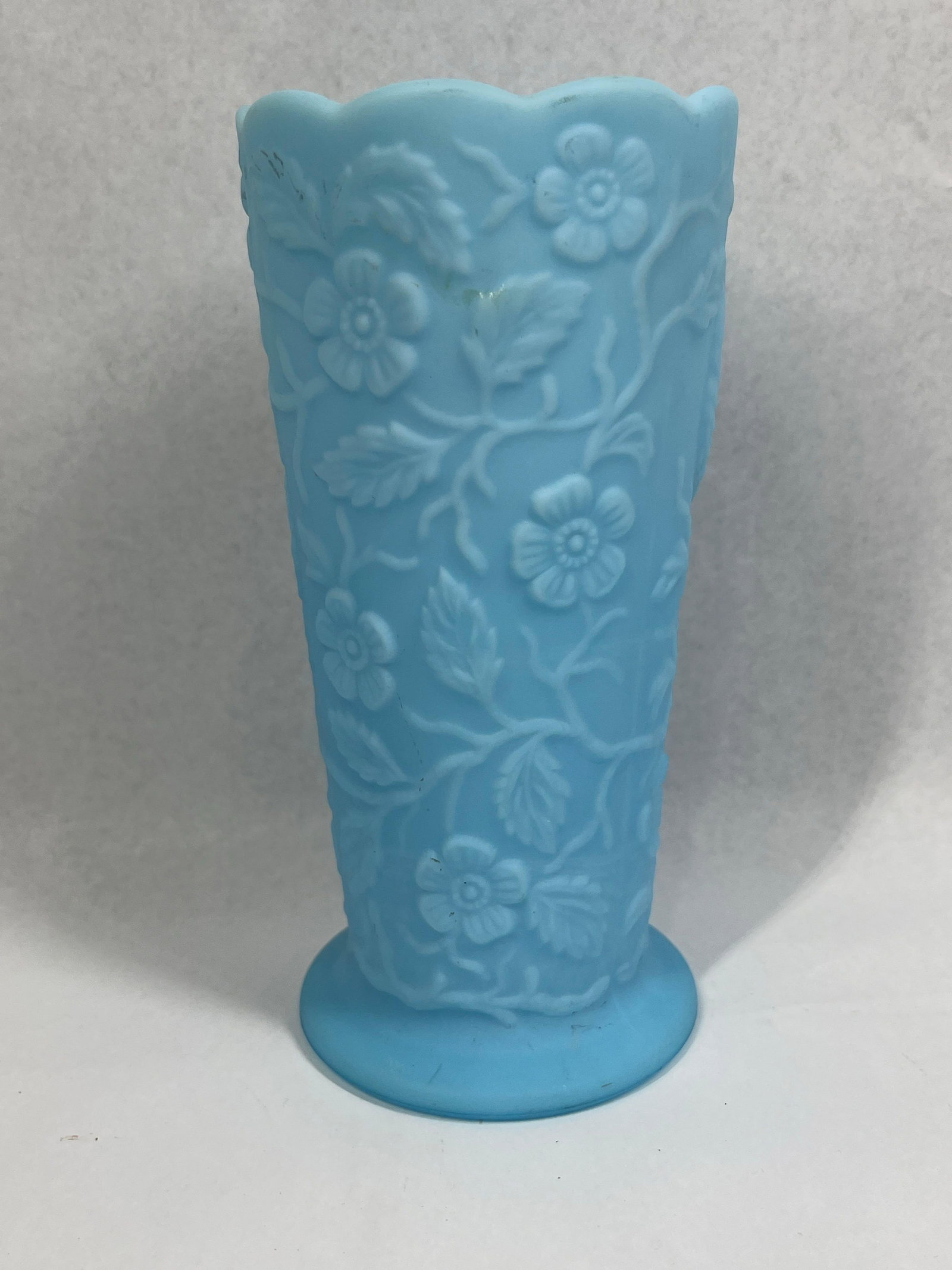 Fenton Blue Satin Peacock Garden Vase: 8in tall A vintage Fenton Art Glass Company vase in the Peacock Garden pattern. The piece is crafted from light blue satin glass, featuring a matte, frosted finish. The cylindrical body is decorated