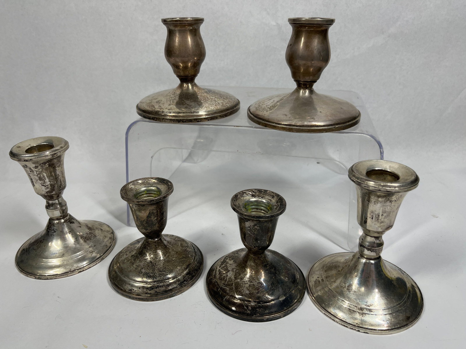 Weighted Sterling Candlesticks: This group of American silver includes multiple pairs of weighted sterling silver candlesticks. The first pair, by Towle Silversmiths, features bell-shaped candle cups on short stems with bulbous