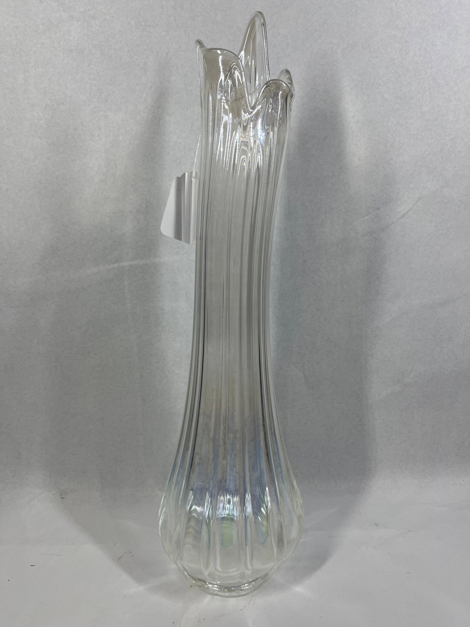 Mid-C. Iridescent Swung Glass Vase: 23in tall This vintage mid-century modern decorative vase is composed of clear glass featuring an overall iridescent finish with a pearlescent luster. The vessel is designed with a bulbous base
